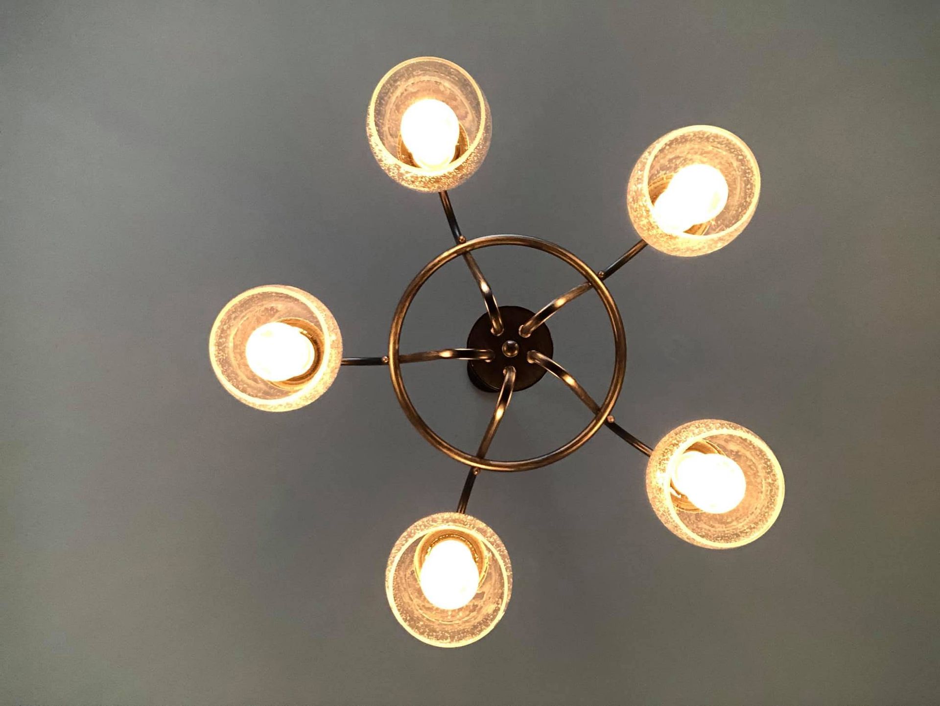 Ceiling light fixture with five glowing bulbs arranged in a circular pattern