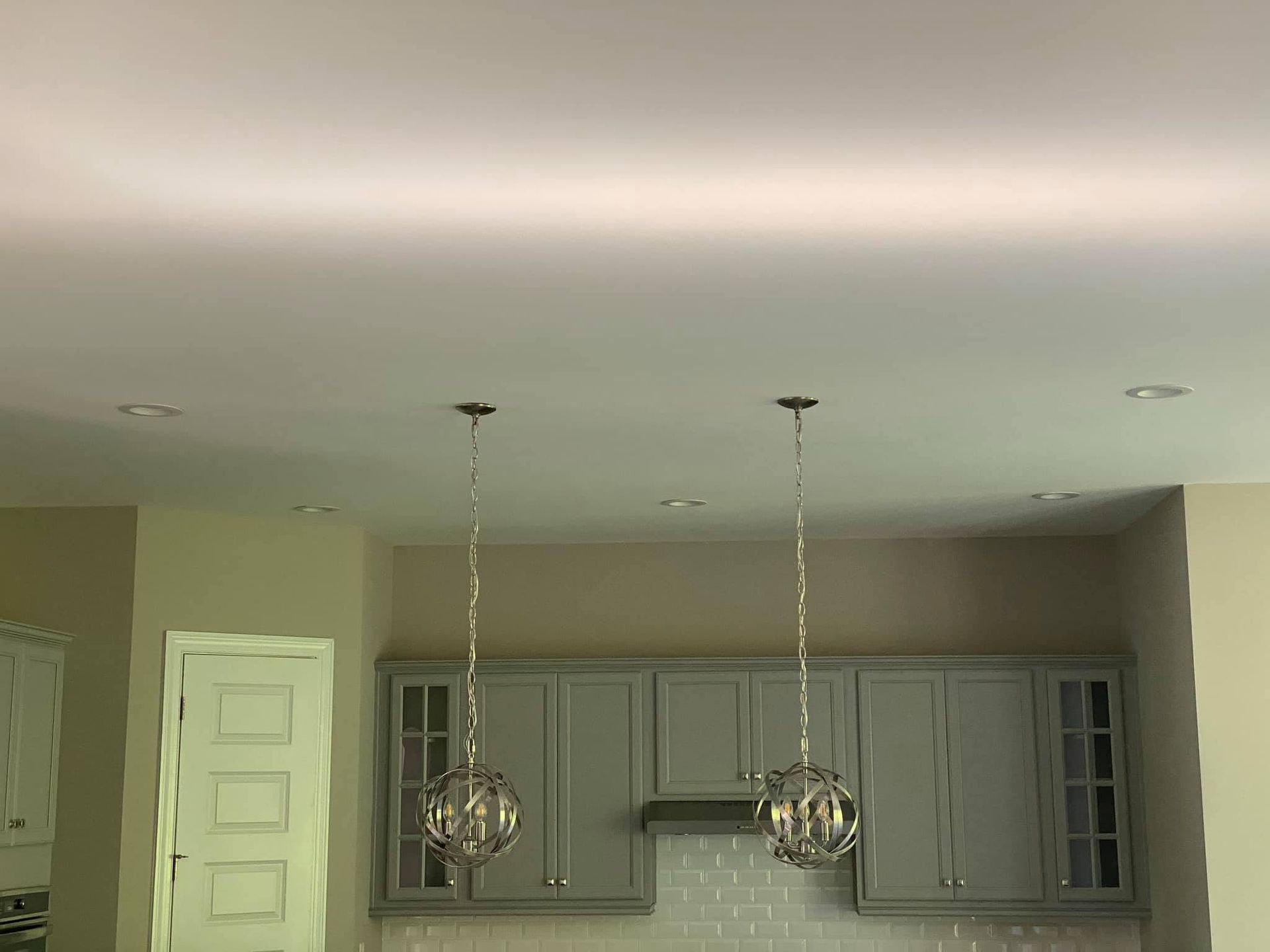 Kitchen with gray cabinets, white ceiling, and two hanging pendant lights