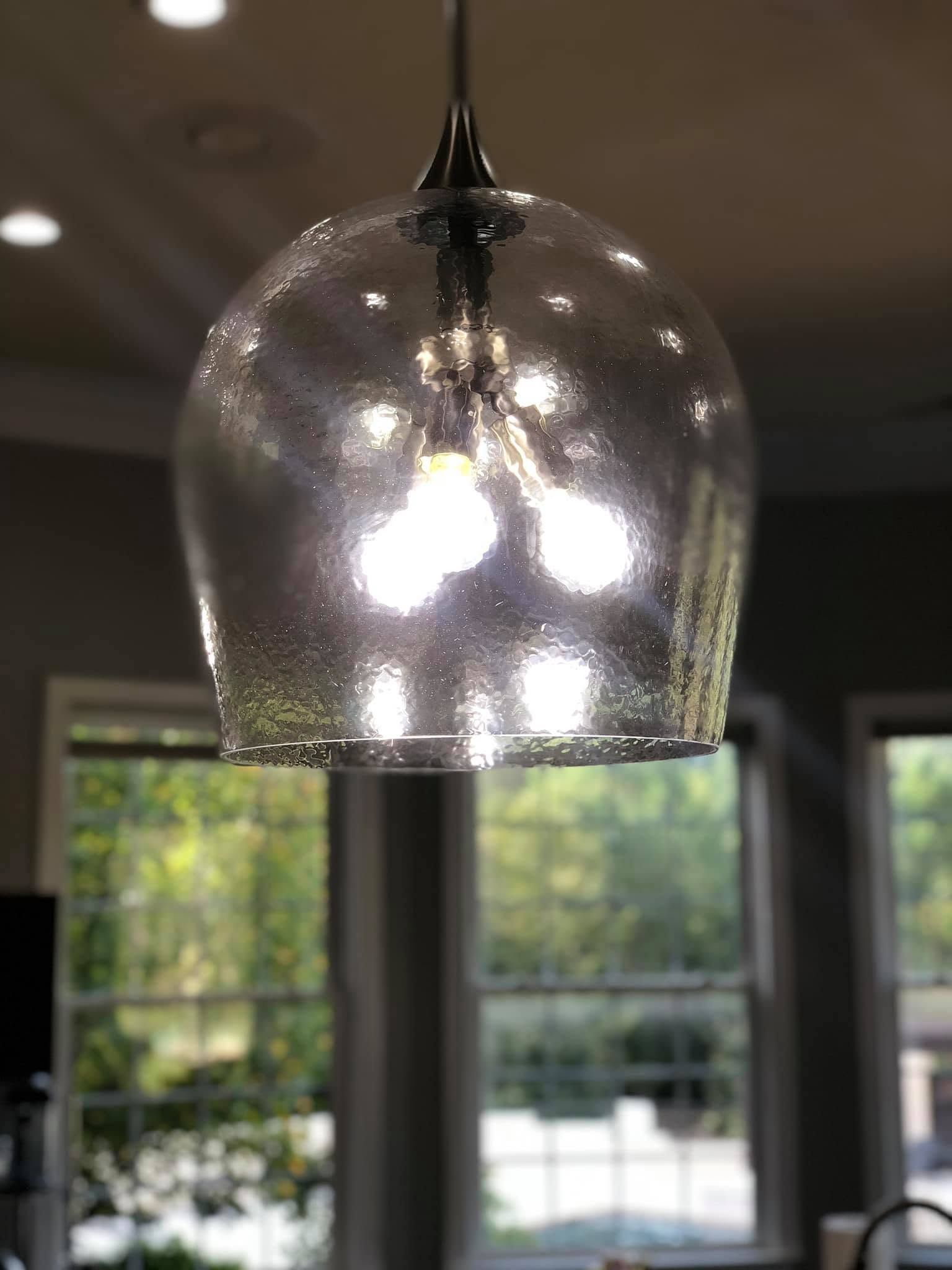 Glass pendant light with bright bulbs hanging indoors near windows