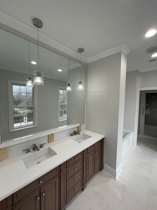 Bathroom vanity with double sinks, large mirror, and pendant lights in a bright modern interior