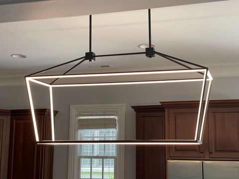 Modern geometric pendant light over a kitchen island, with wood cabinets in the background