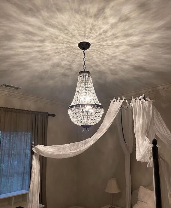 Crystal chandelier in a softly lit room with sheer white drapes and window curtains