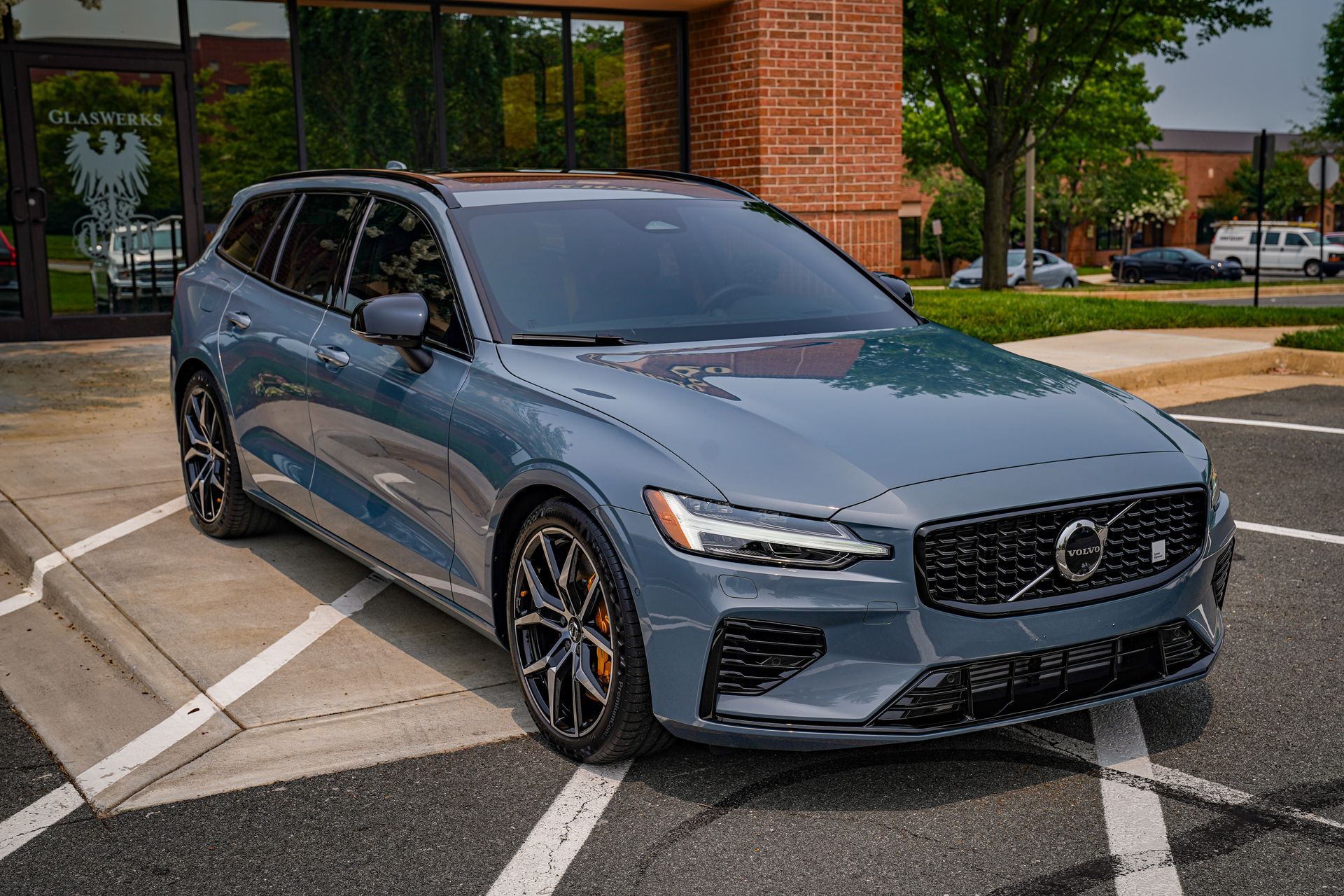 A volvo v60 station wagon is parked in a parking lot in front of a building.