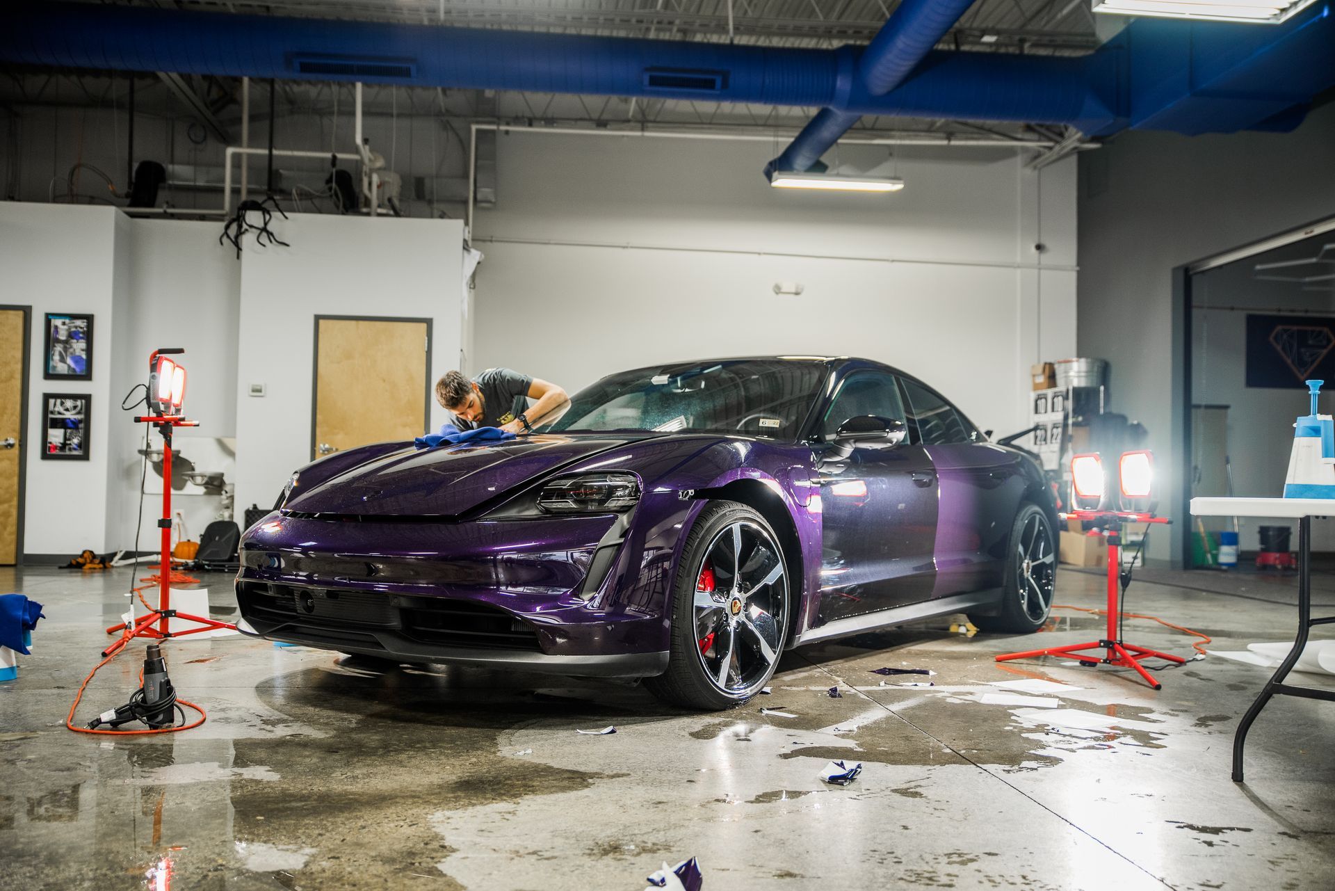 a technician applying purple color-change film to a Porsche