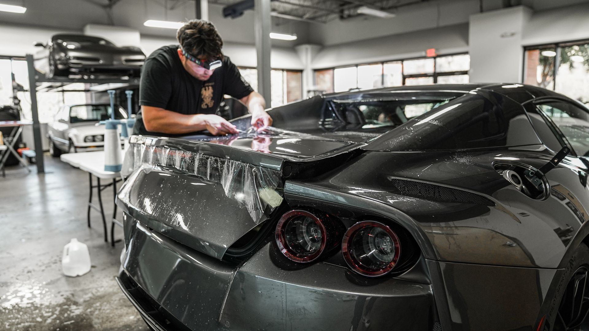 A man is painting a car in a garage.