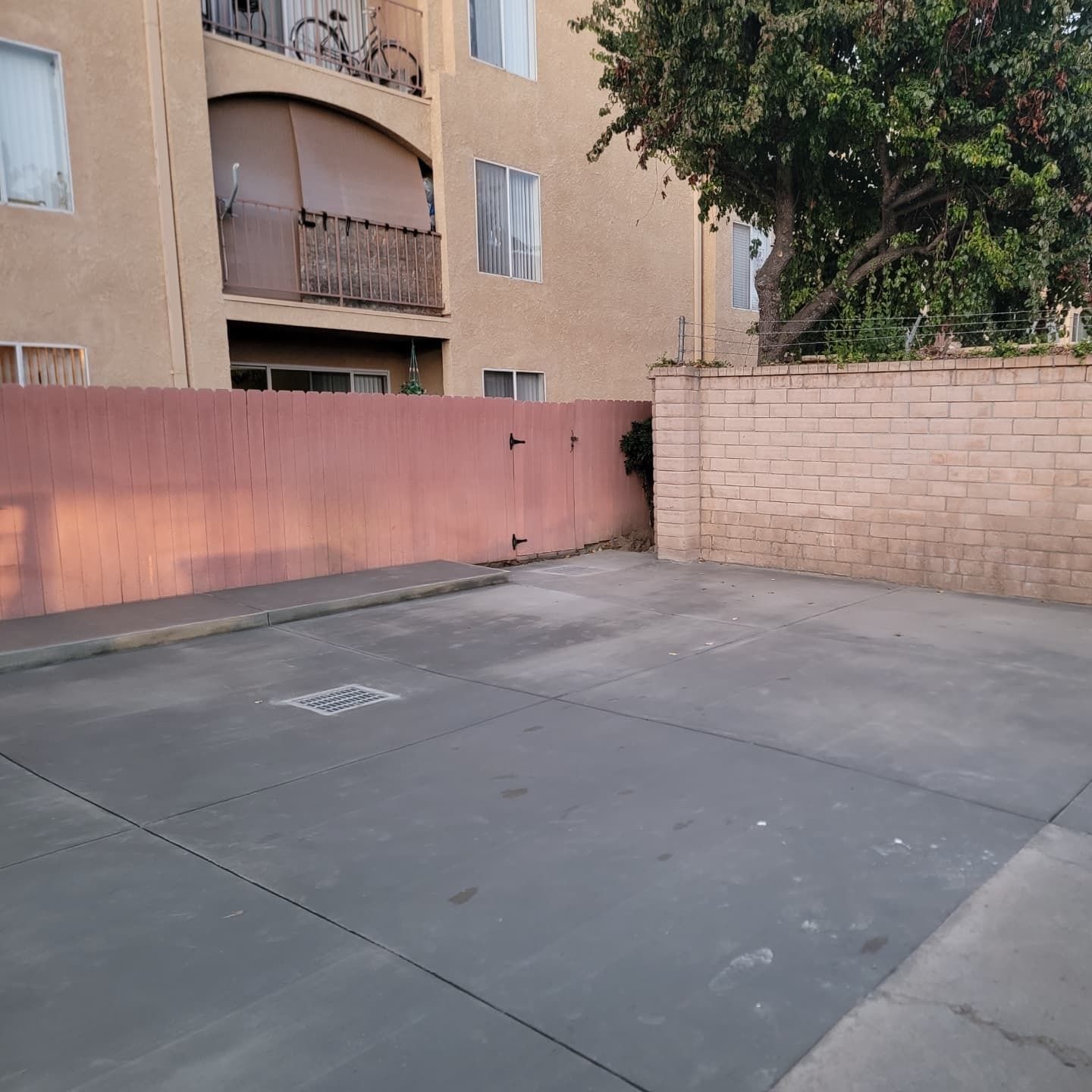 Empty concrete lot next to a peach-colored wall and apartment building.