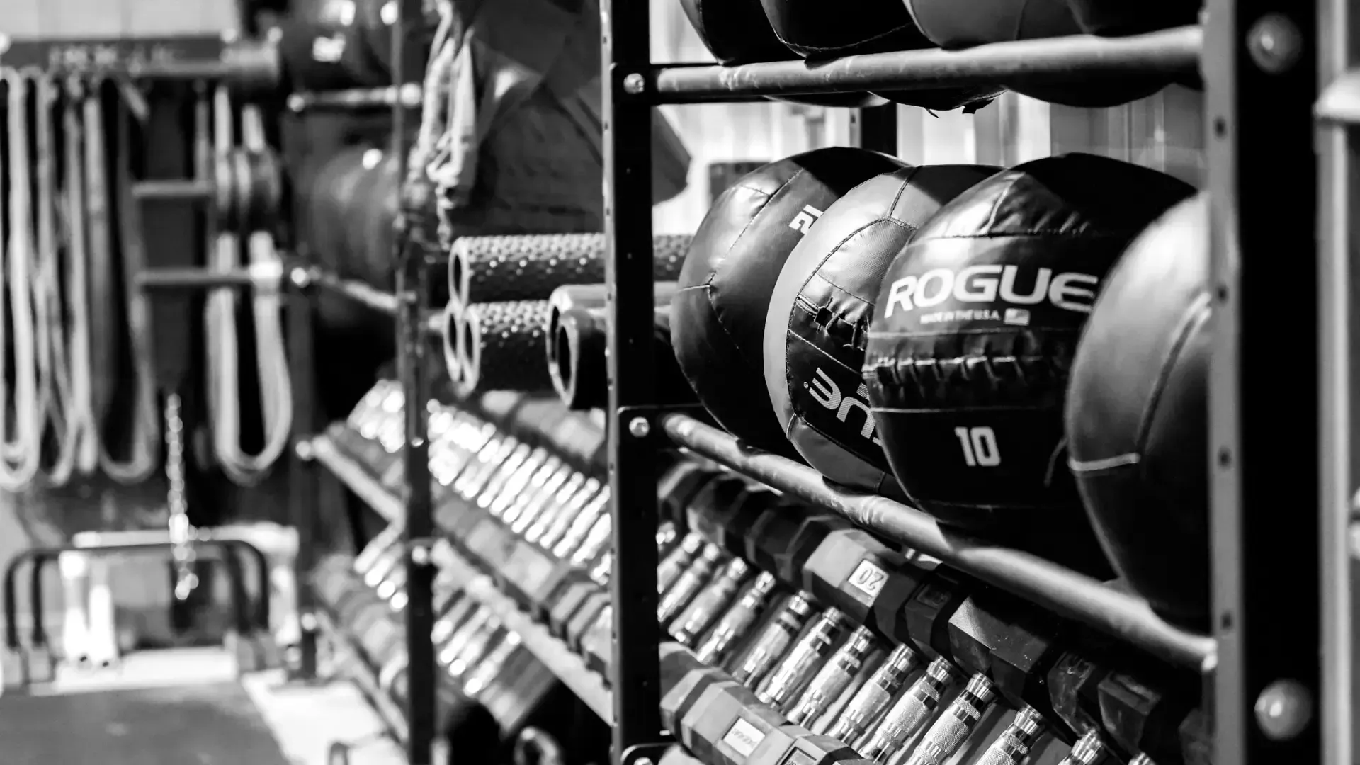 Gym rack with medicine balls and dumbbells in a black-and-white training room