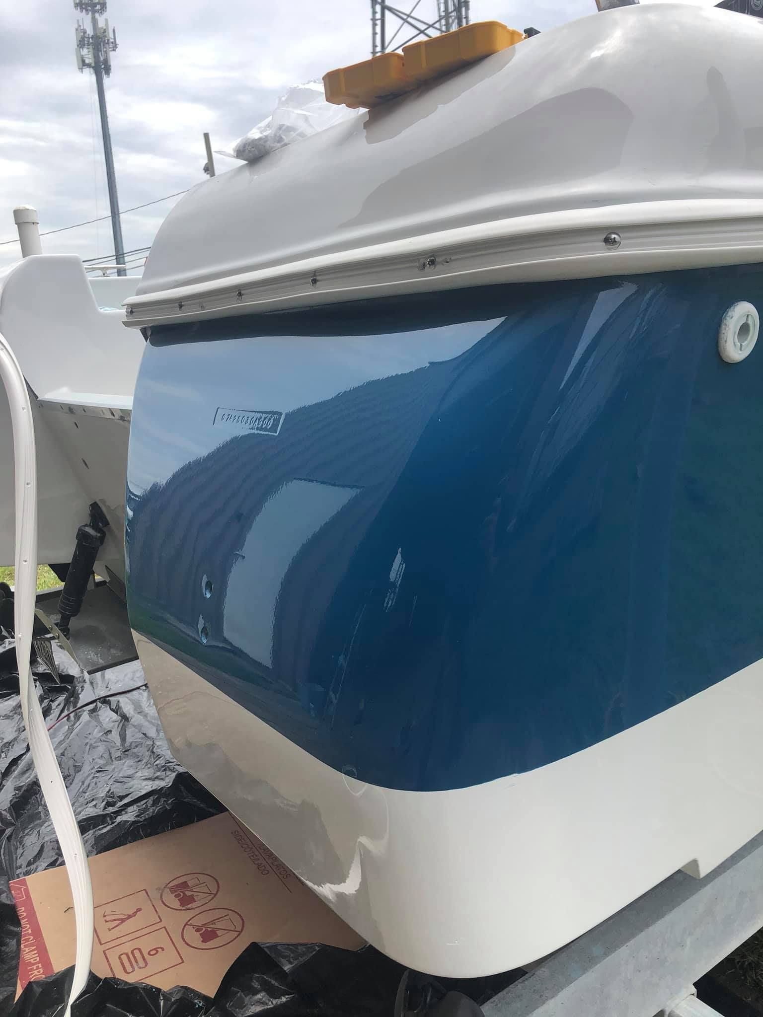 Blue-and-white boat hull on a trailer, viewed from the front-left side.