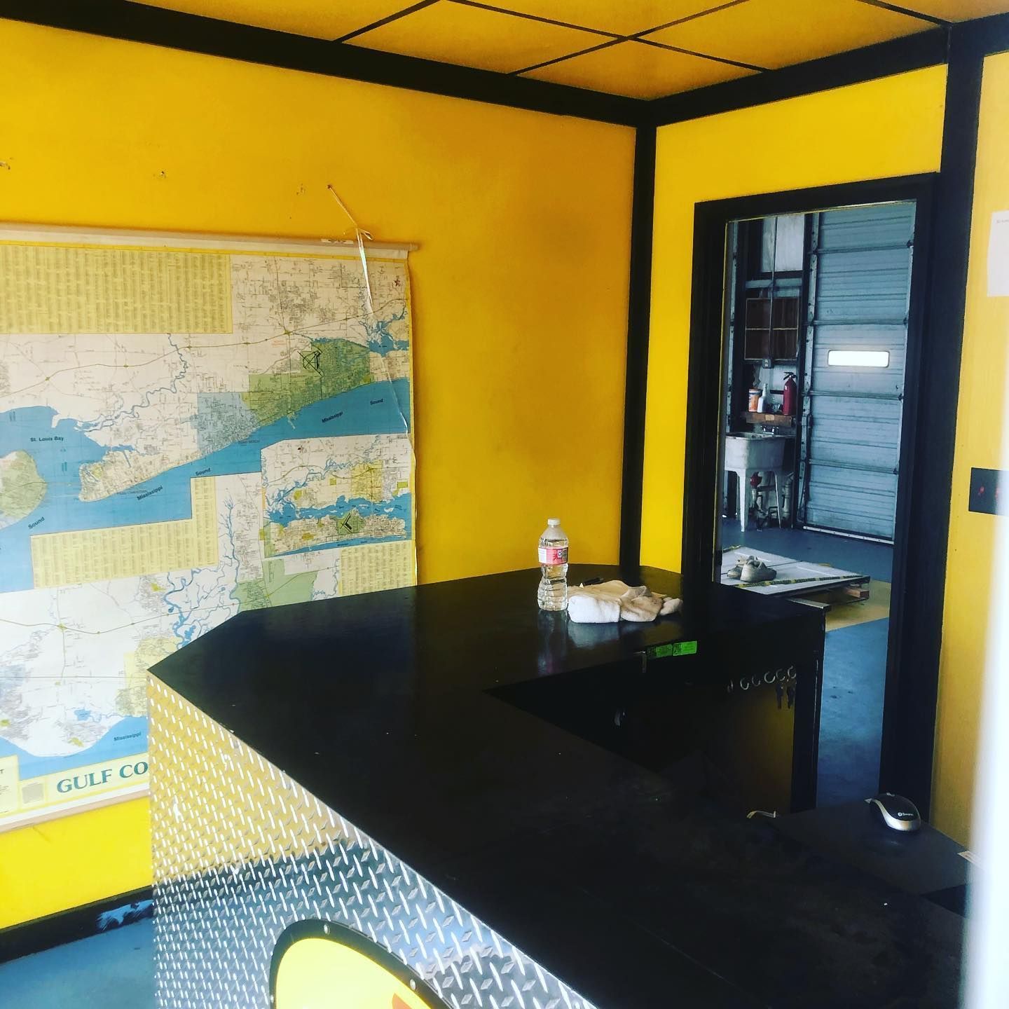 Small office with yellow walls, a large map, and a black counter near an open doorway.