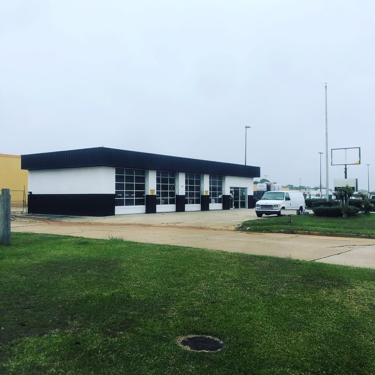 Low black-and-white building beside a parking lot under an overcast sky