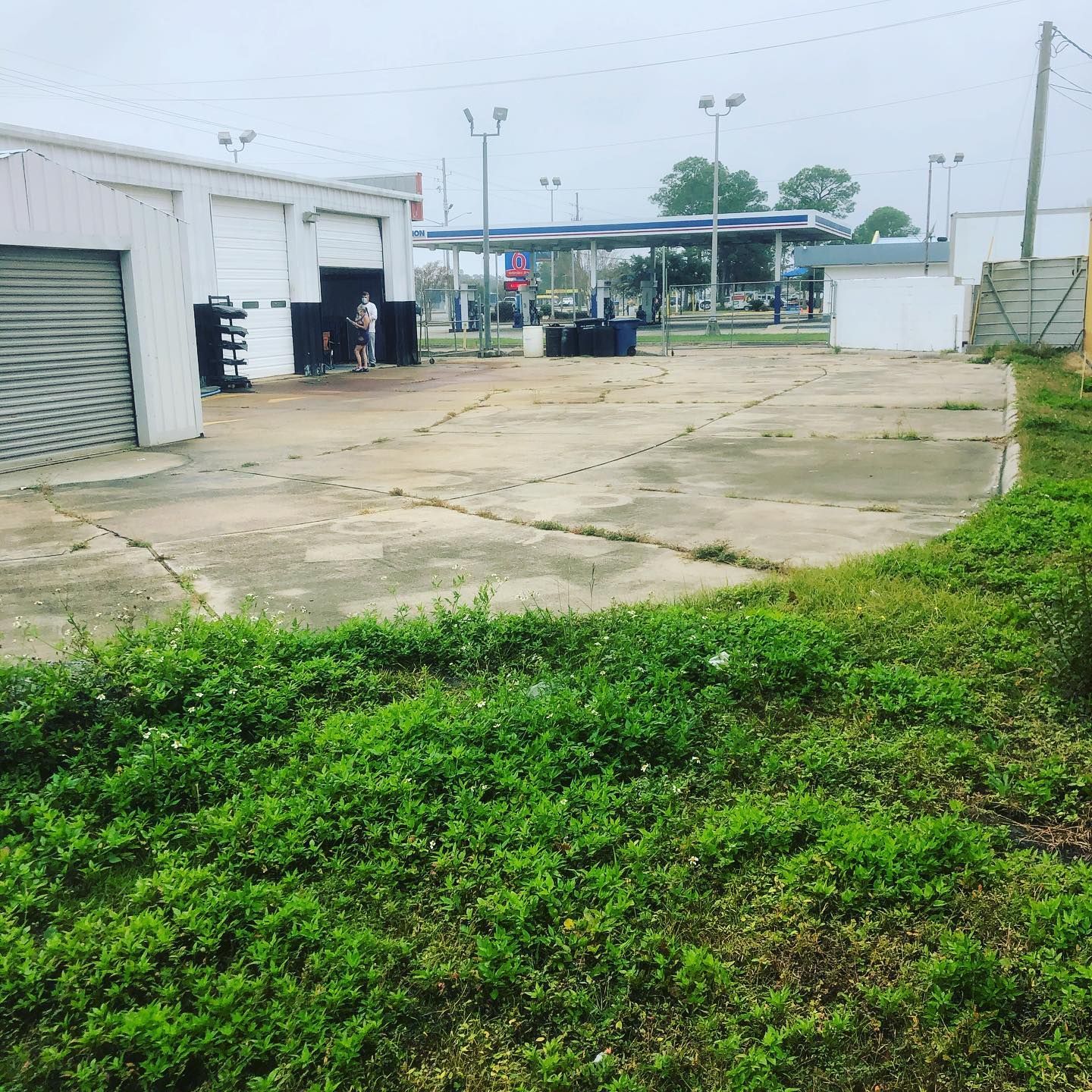 Industrial lot with white buildings, concrete yard, and green grass in the foreground.
