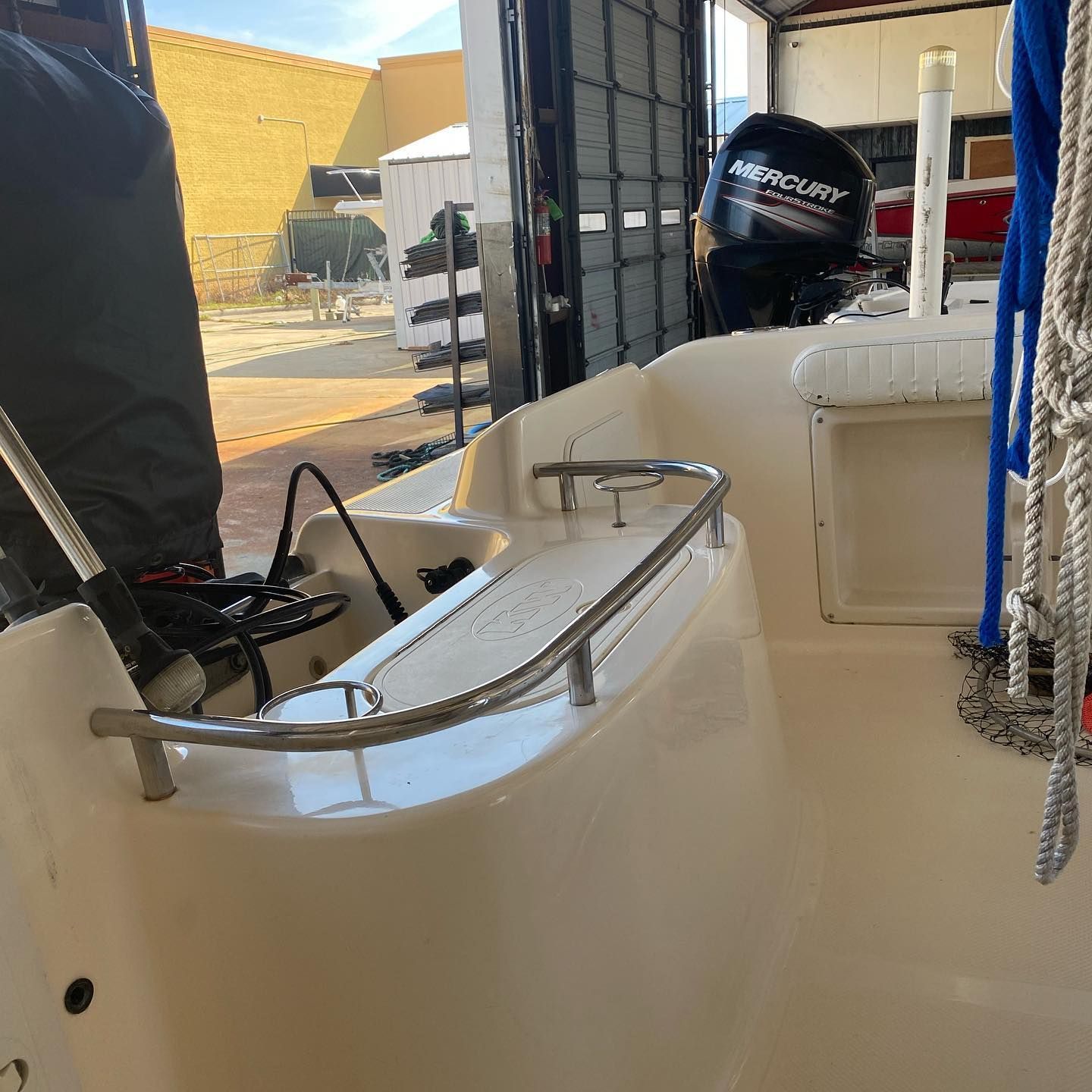 White boat cockpit with black outboard motor and metal railings in a marina or dock area