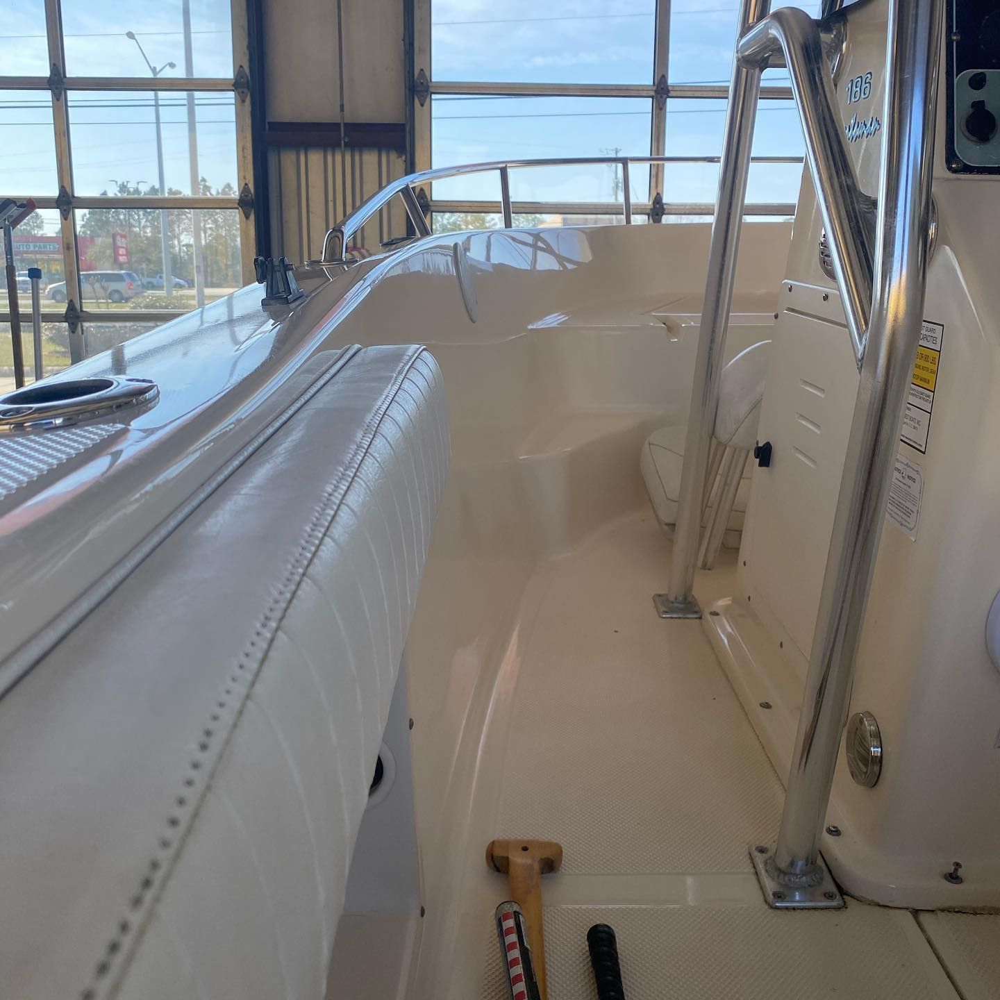 Narrow boat cabin with white seating, beige deck, and large windows overlooking the water