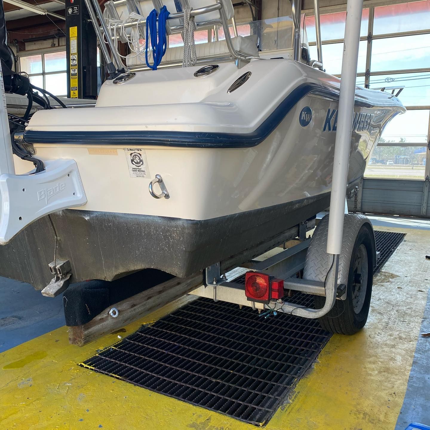 White-and-black boat on a trailer, parked in a covered marina area over a floor drain grate