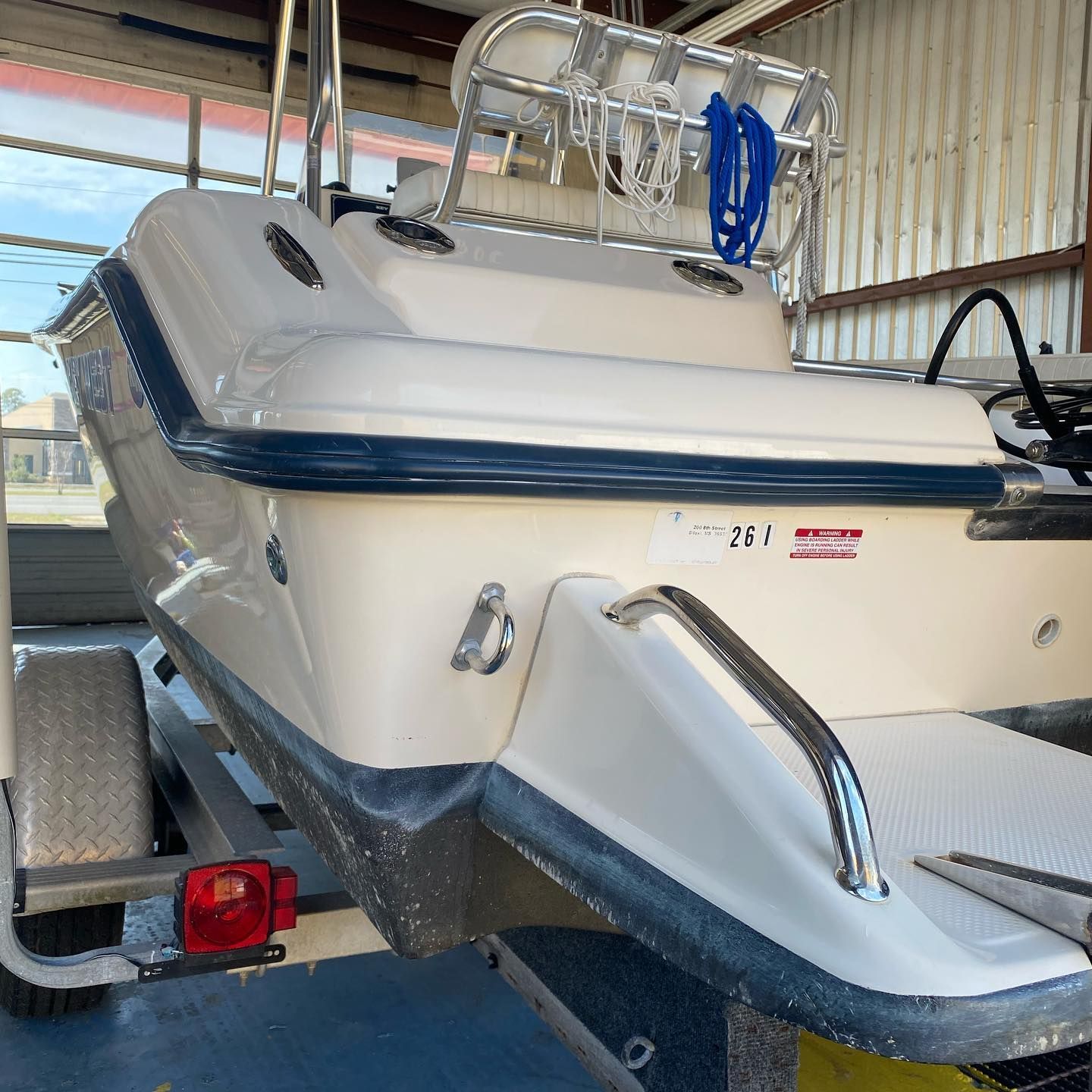Cream and blue boat on a trailer inside a covered garage or workshop.