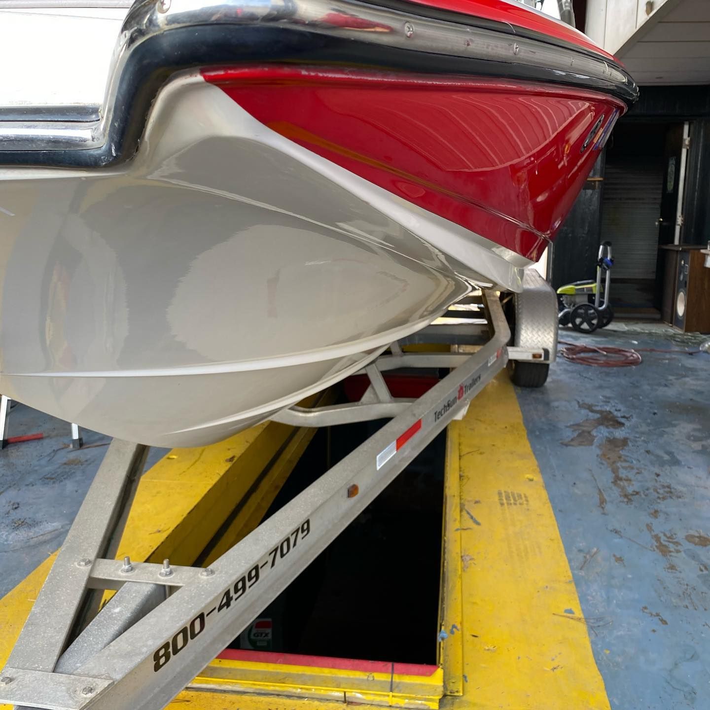 Close-up of a white and red boat on a trailer inside a boat service bay