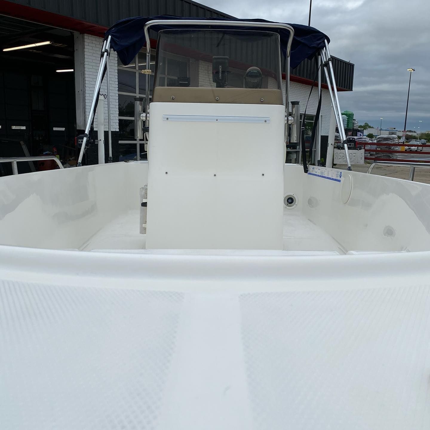White boat cockpit with a center console and blue canopy, docked at a marina.