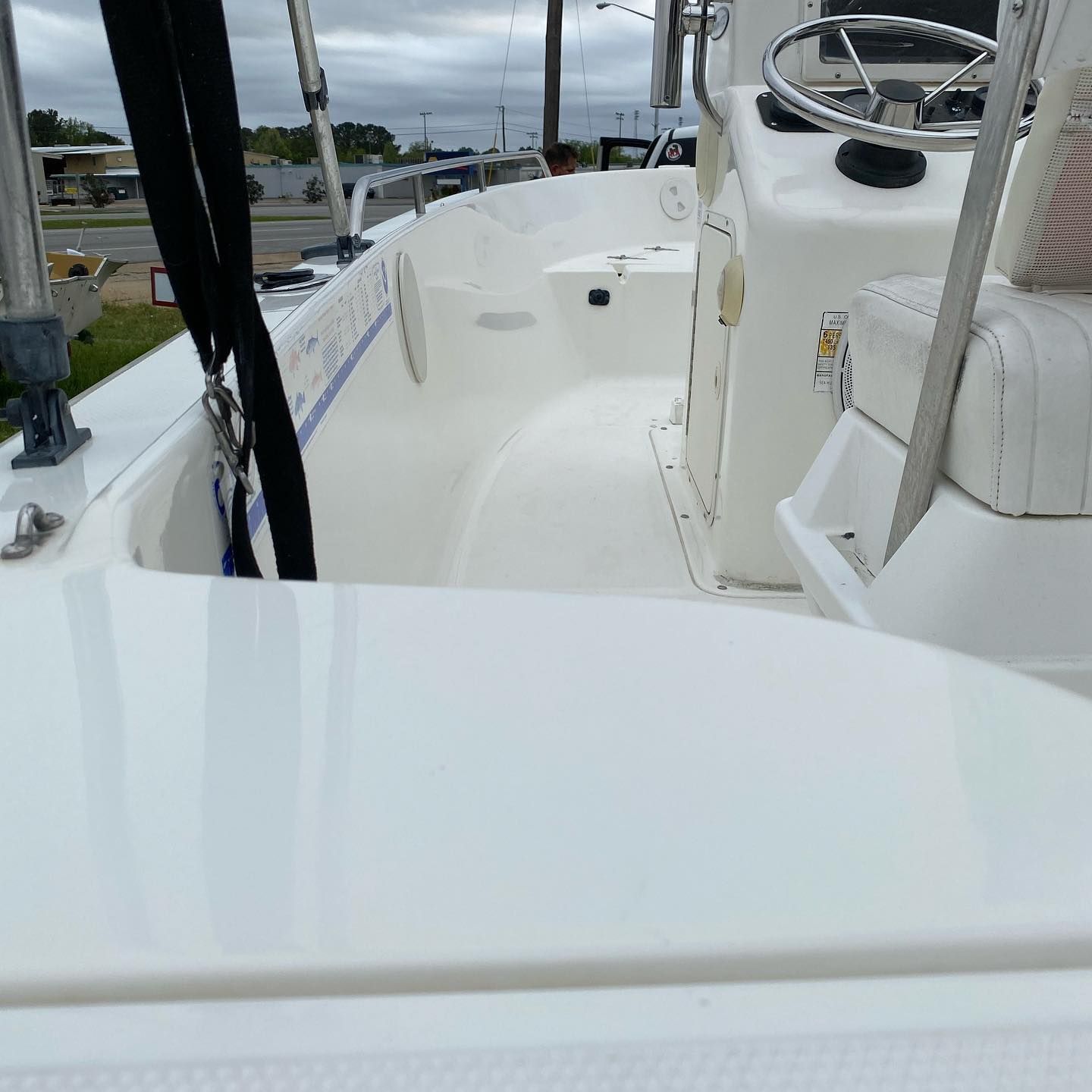 View from a boat deck with white seating, steering wheel, and marina scenery in the background