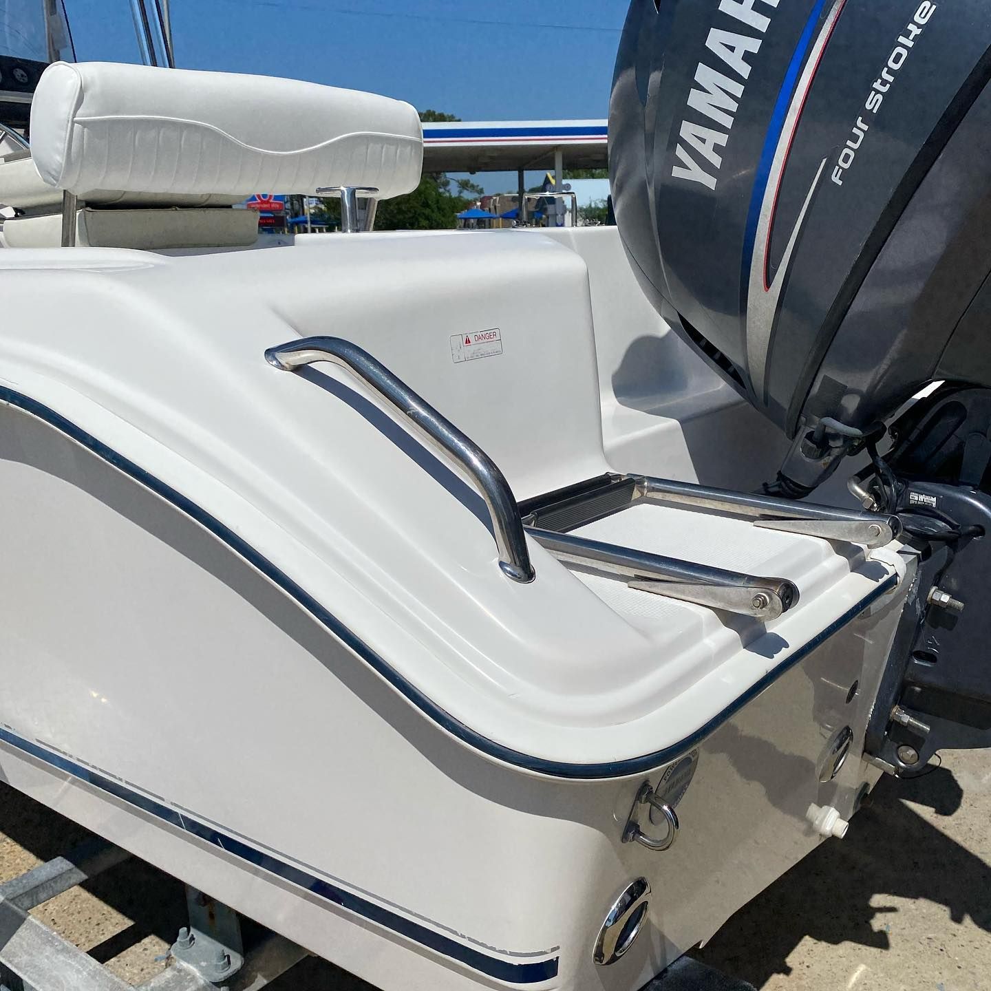 White boat stern with a cushioned seat and Yamaha outboard motor on a sunny day