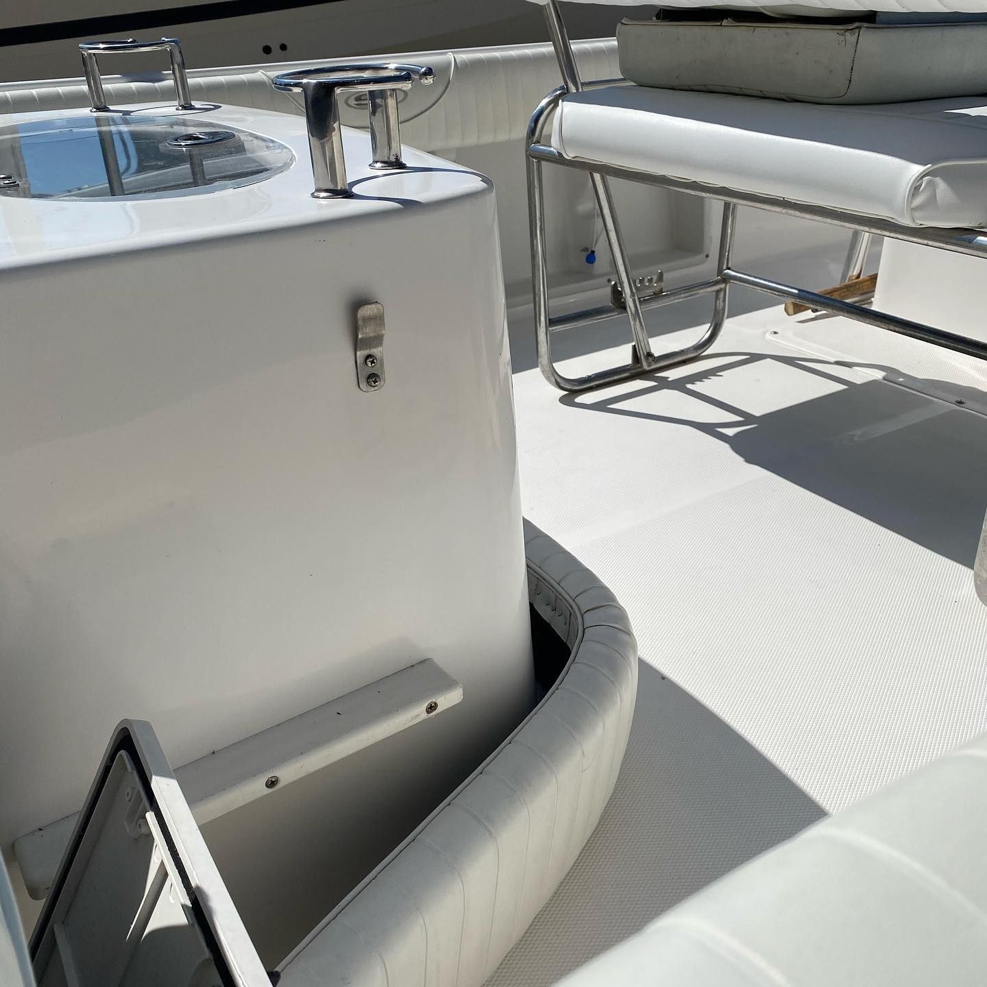 White boat cockpit with sink, faucet, bench seat, and bright deck in sunlight