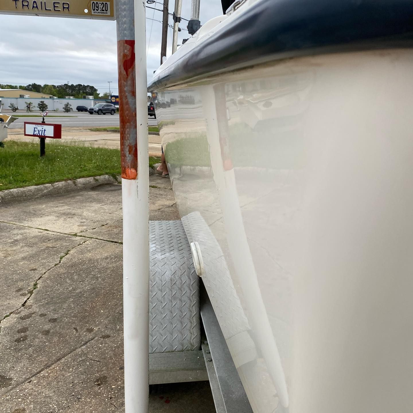 White boat hull beside a dock post, with a tire fender and marina water in the background