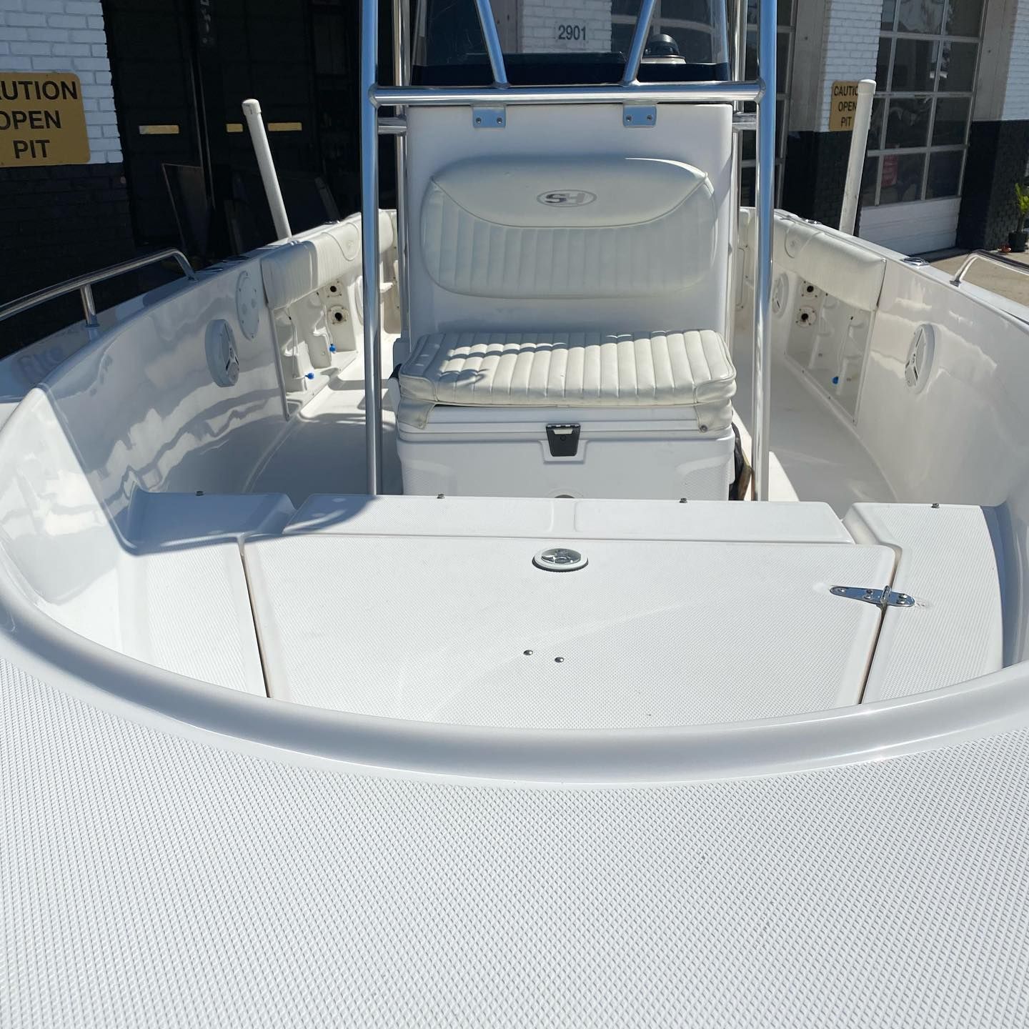 White center-console fishing boat deck with a leaning post and storage hatch at the dock.
