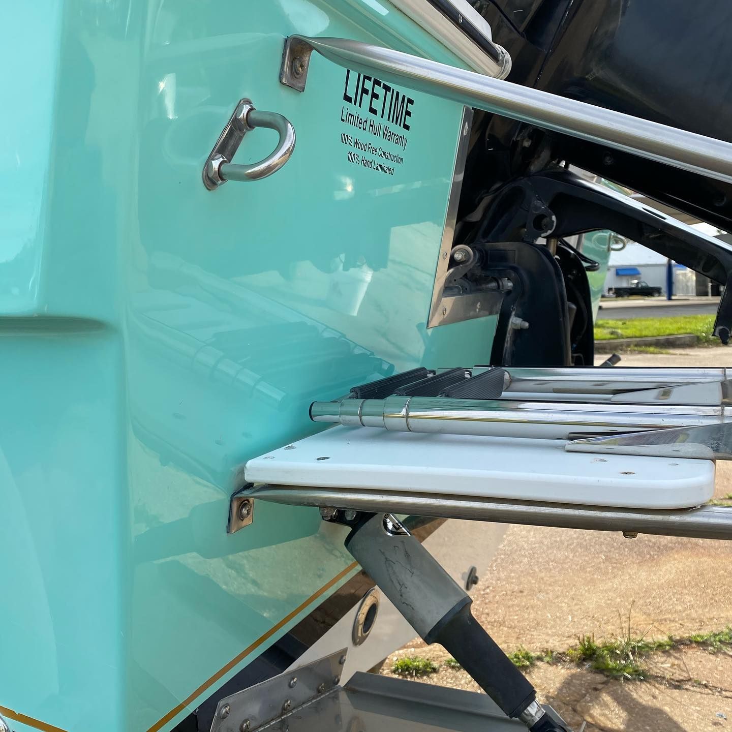 Close-up of a turquoise boat hull with a metal swim platform and black support strut.