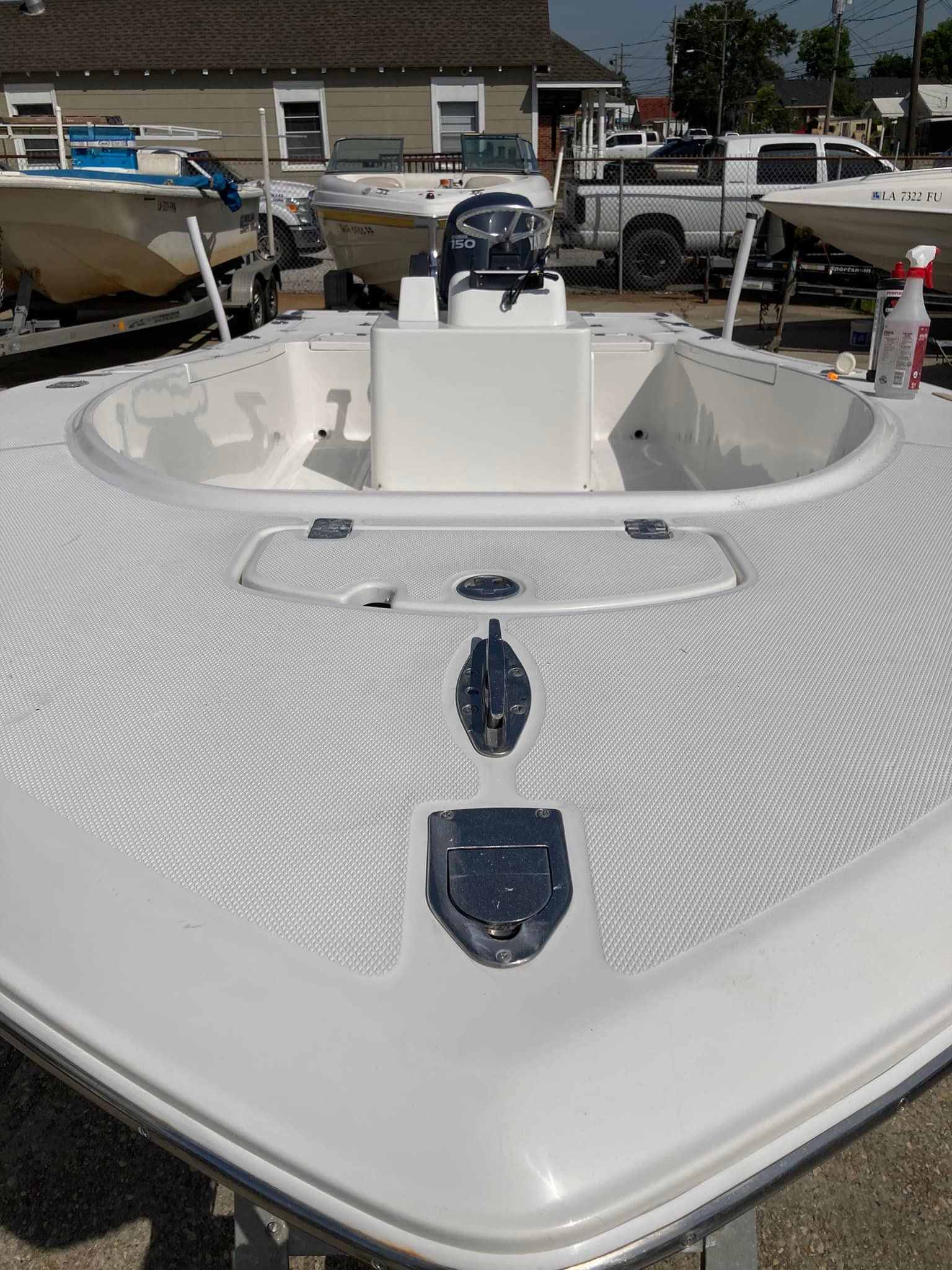 White boat bow with open center console, shown on a trailer in a parking lot.