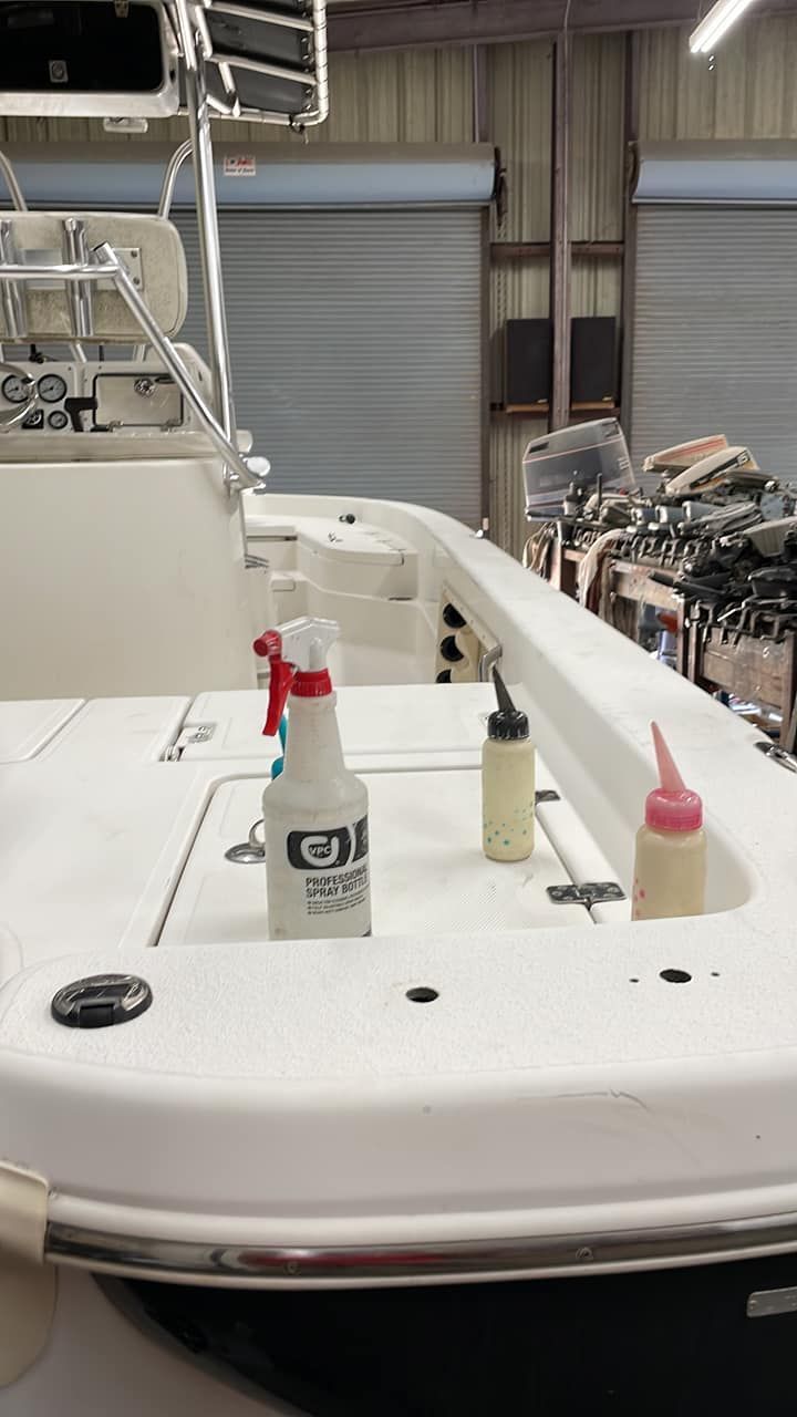 White boat deck with spray bottles and a covered seat in a marina or workshop setting