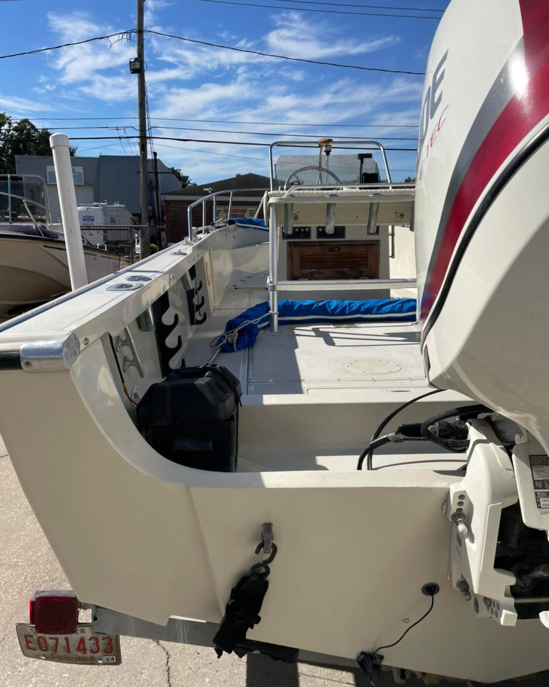 Boat stern deck with white outboard motor and open storage on a sunny marina dock