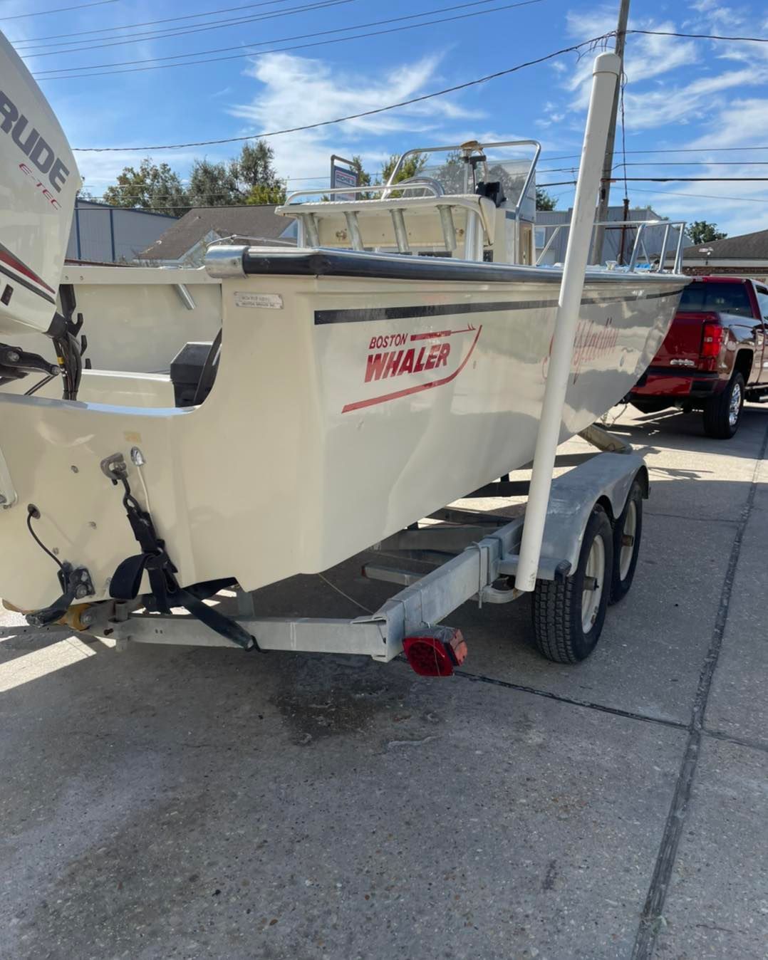White boat on trailer in a parking lot, with red lettering on the hull.