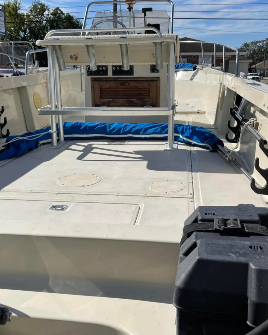 Empty white boat deck with center console, blue tarp, and water in the background