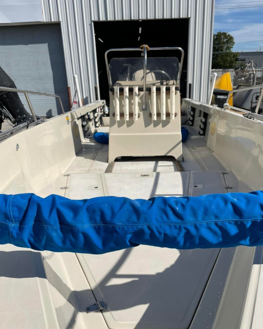 White boat deck with blue rail cover and stainless equipment mounted at the stern.