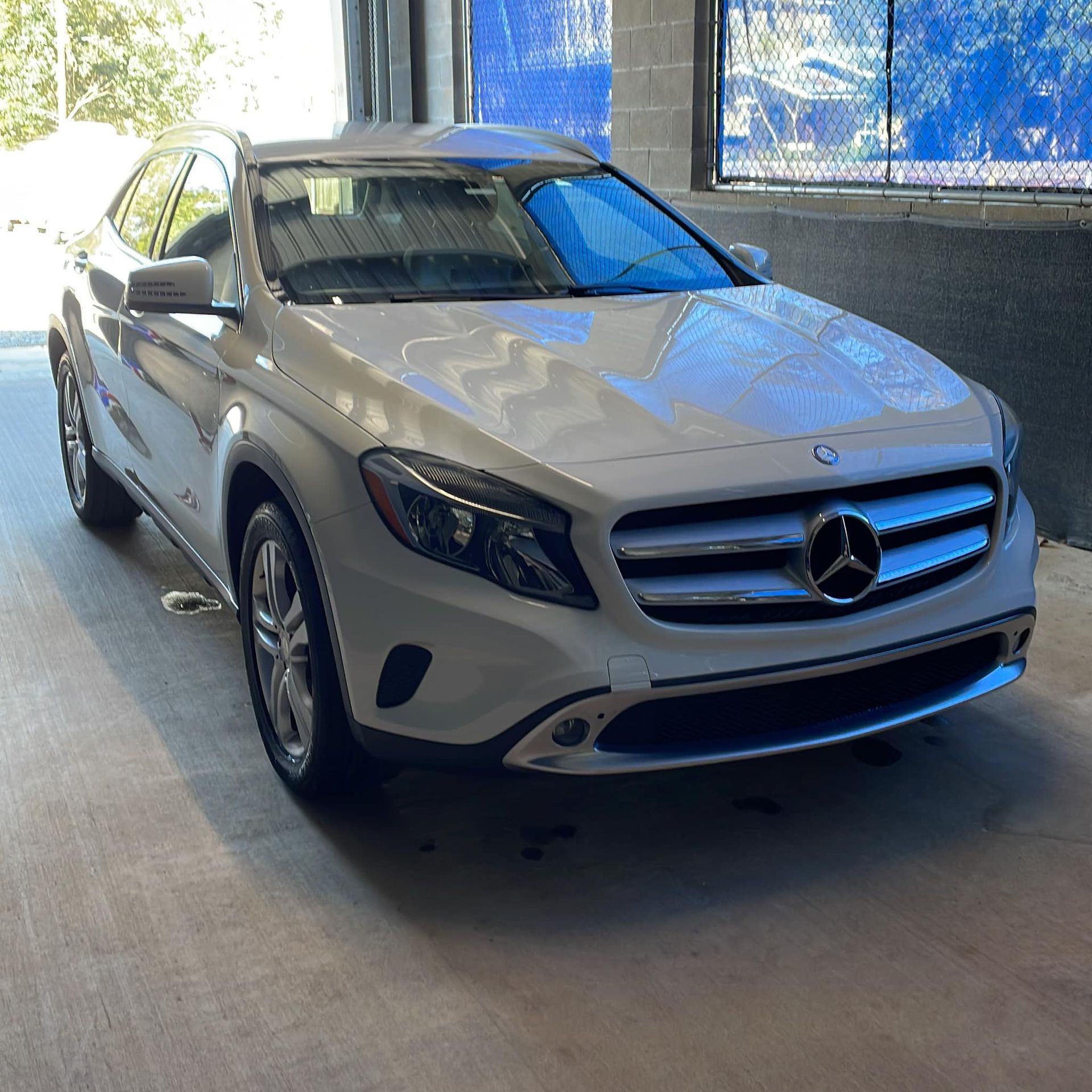 White Mercedes-Benz SUV parked indoors on a concrete floor, viewed from the front-left side.