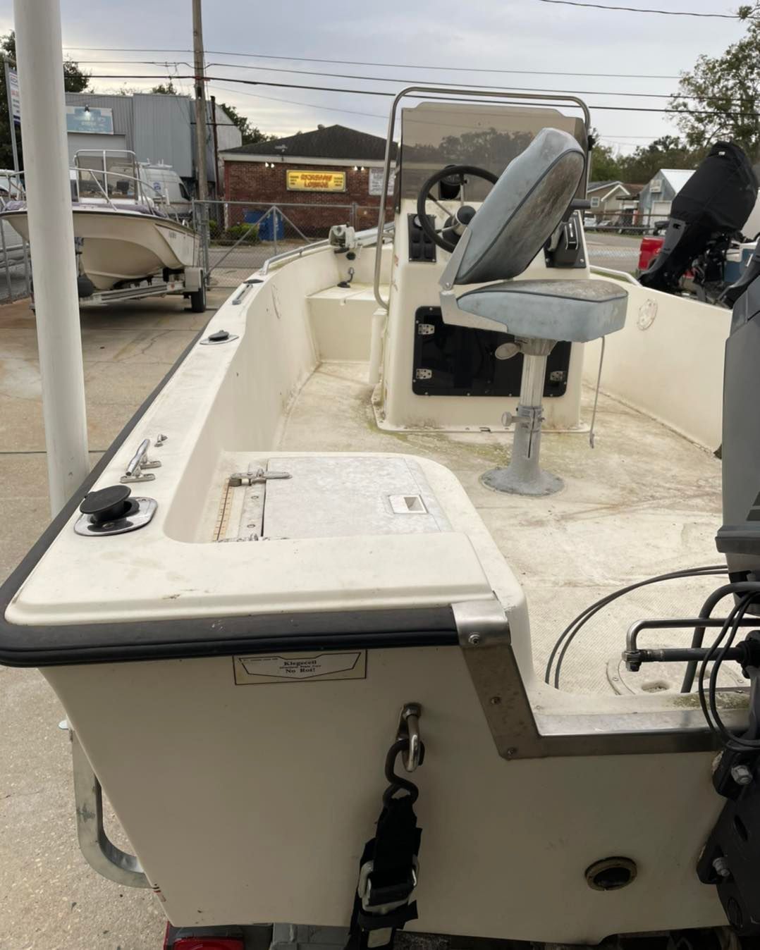 Boat cockpit with white deck, gray swivel seat, and center console on a docked boat.
