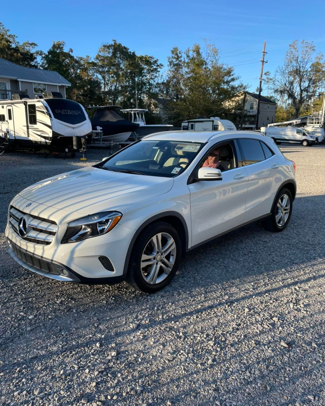 Silver Mercedes SUV on a gravel lot with a driver visible through the open window.