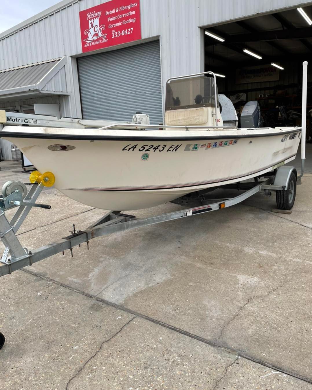 White fishing boat on a trailer parked outside an industrial warehouse