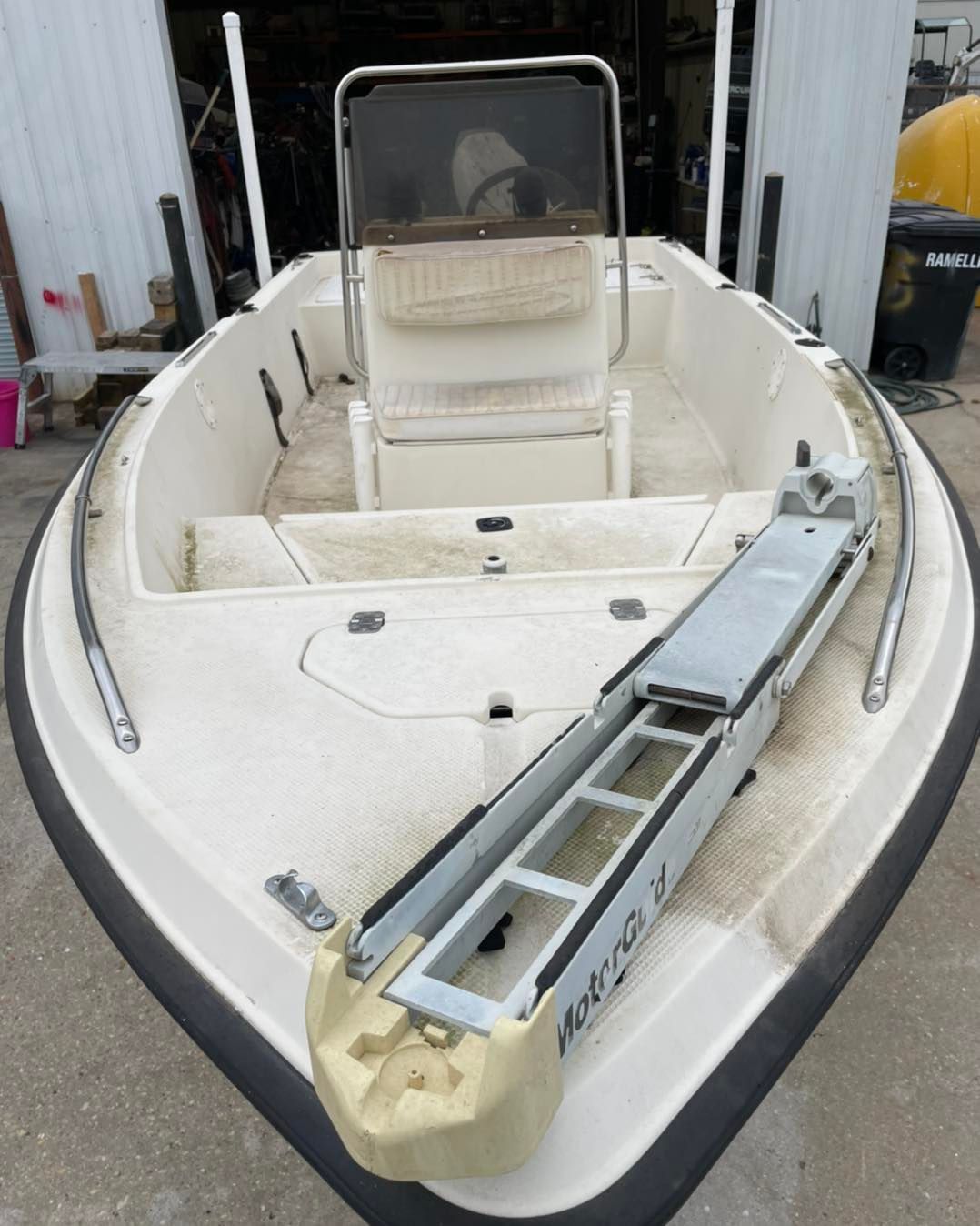 Small white boat with a center console and a metal ladder resting on the bow.