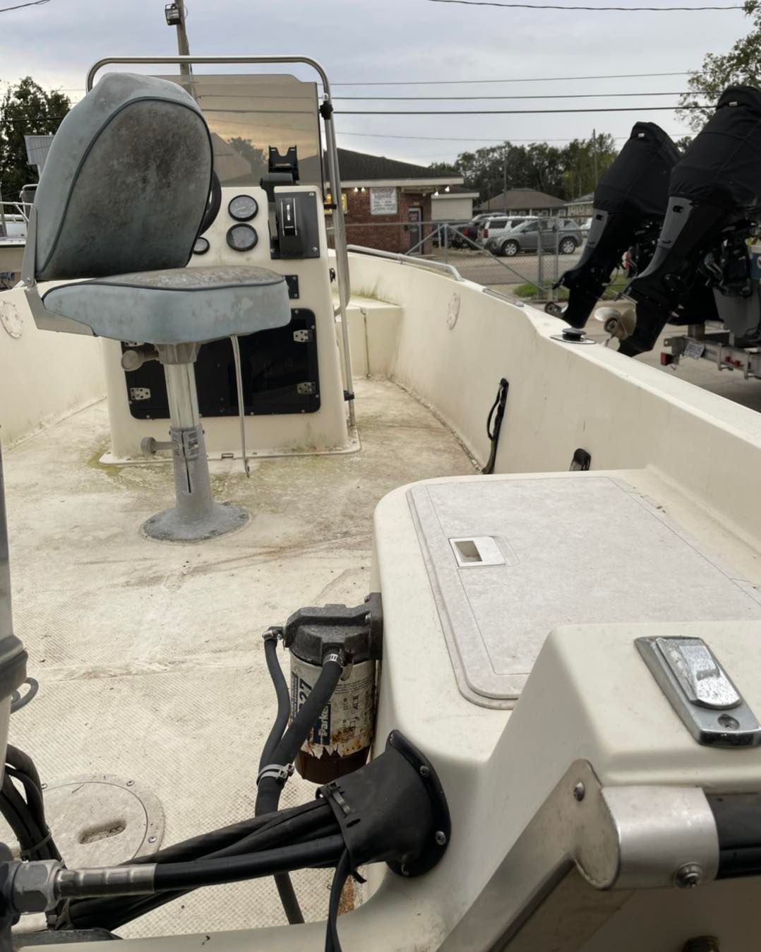 Boat deck with steering seat, console, and mounted fishing rods on a white open boat