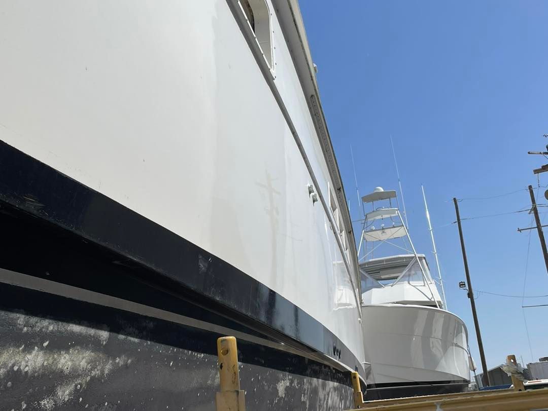 Large white boat hulls at a marina, viewed from below against a blue sky.