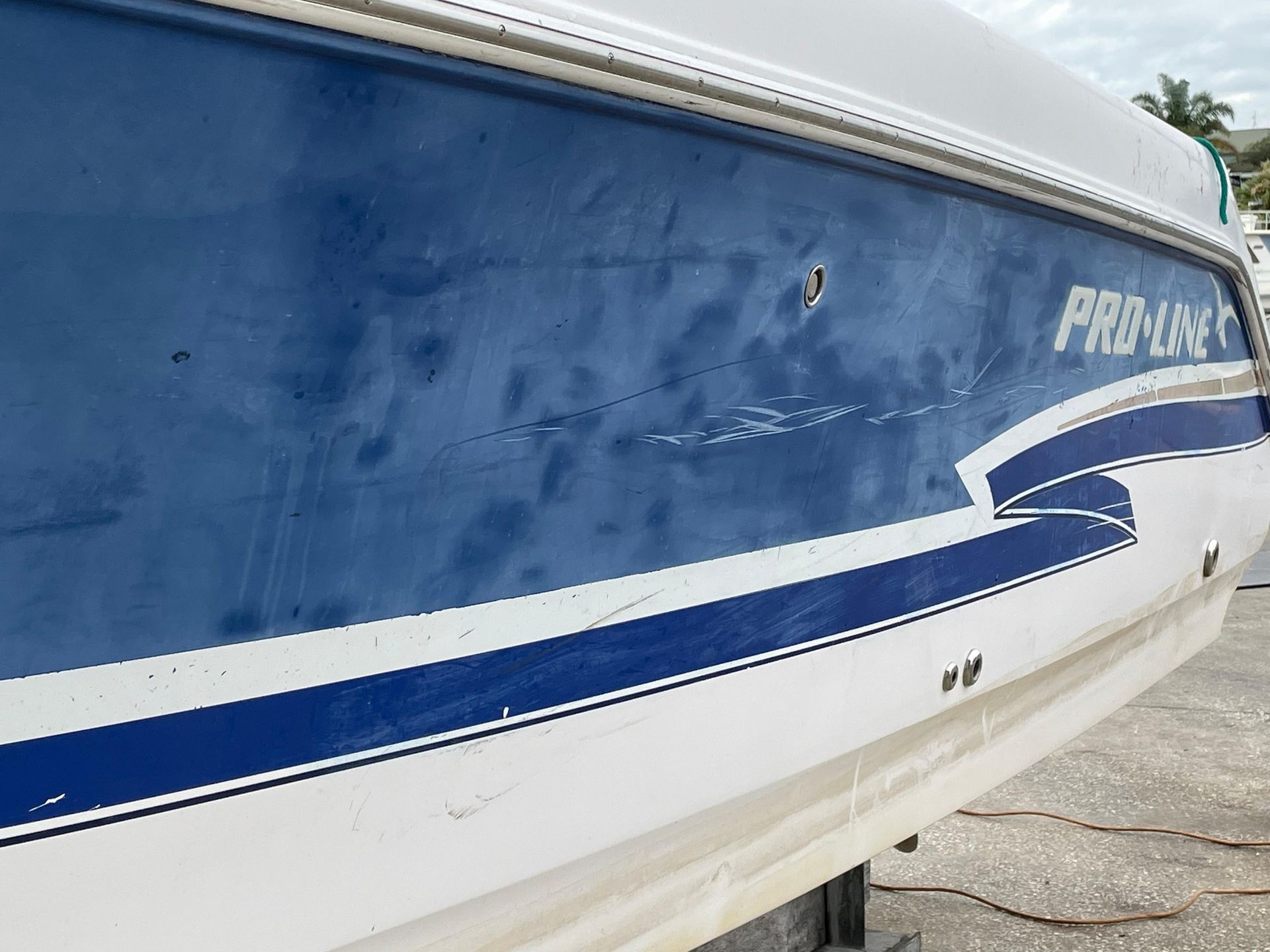Blue and white boat hull with a silver rail and logo lettering near the stern