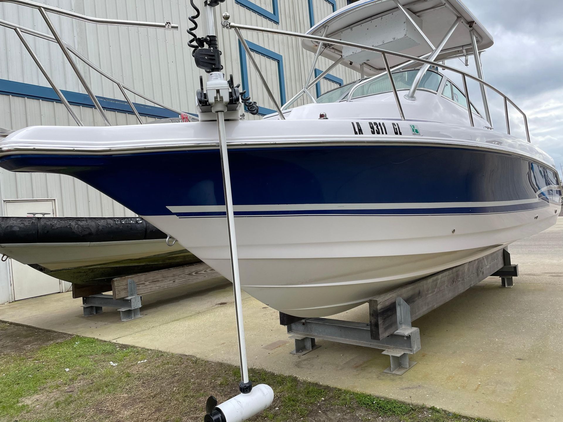 Blue and white boat on stands in a dry dock by a warehouse