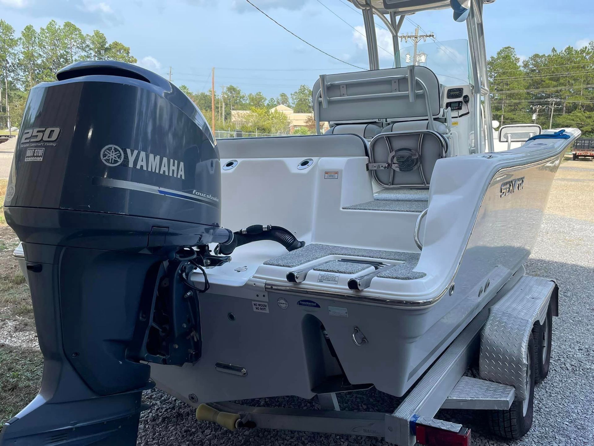 White fishing boat with a black Yamaha outboard motor and center console on a trailer outdoors