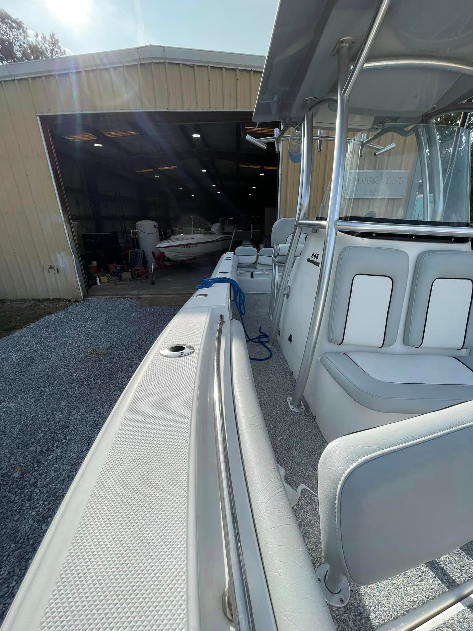 White boat docked by a garage, with a covered seating area in the foreground.