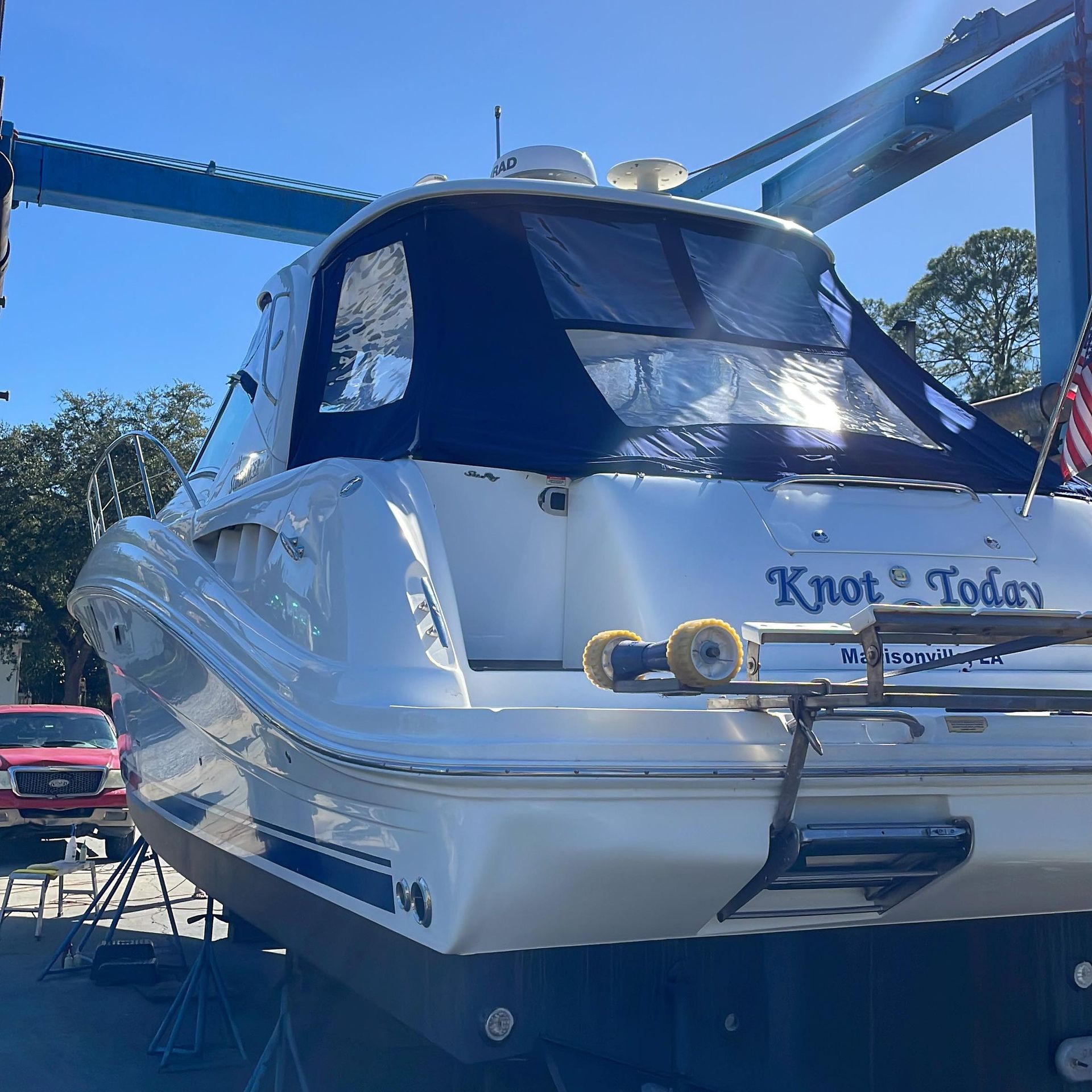 White yacht named “Knot Today” docked under a blue boat lift on a sunny day.