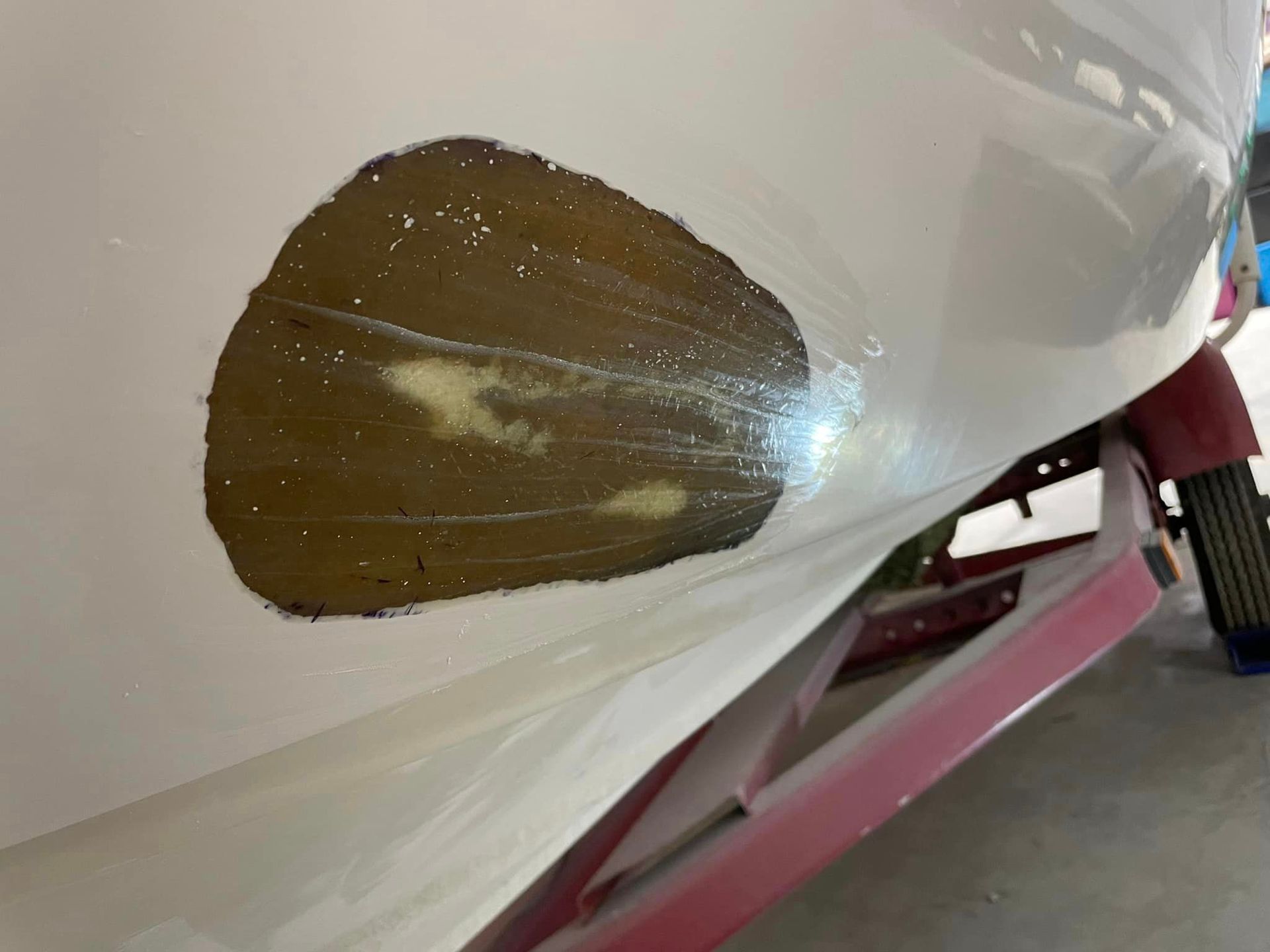 Brown scrape on white car panel near the wheel well