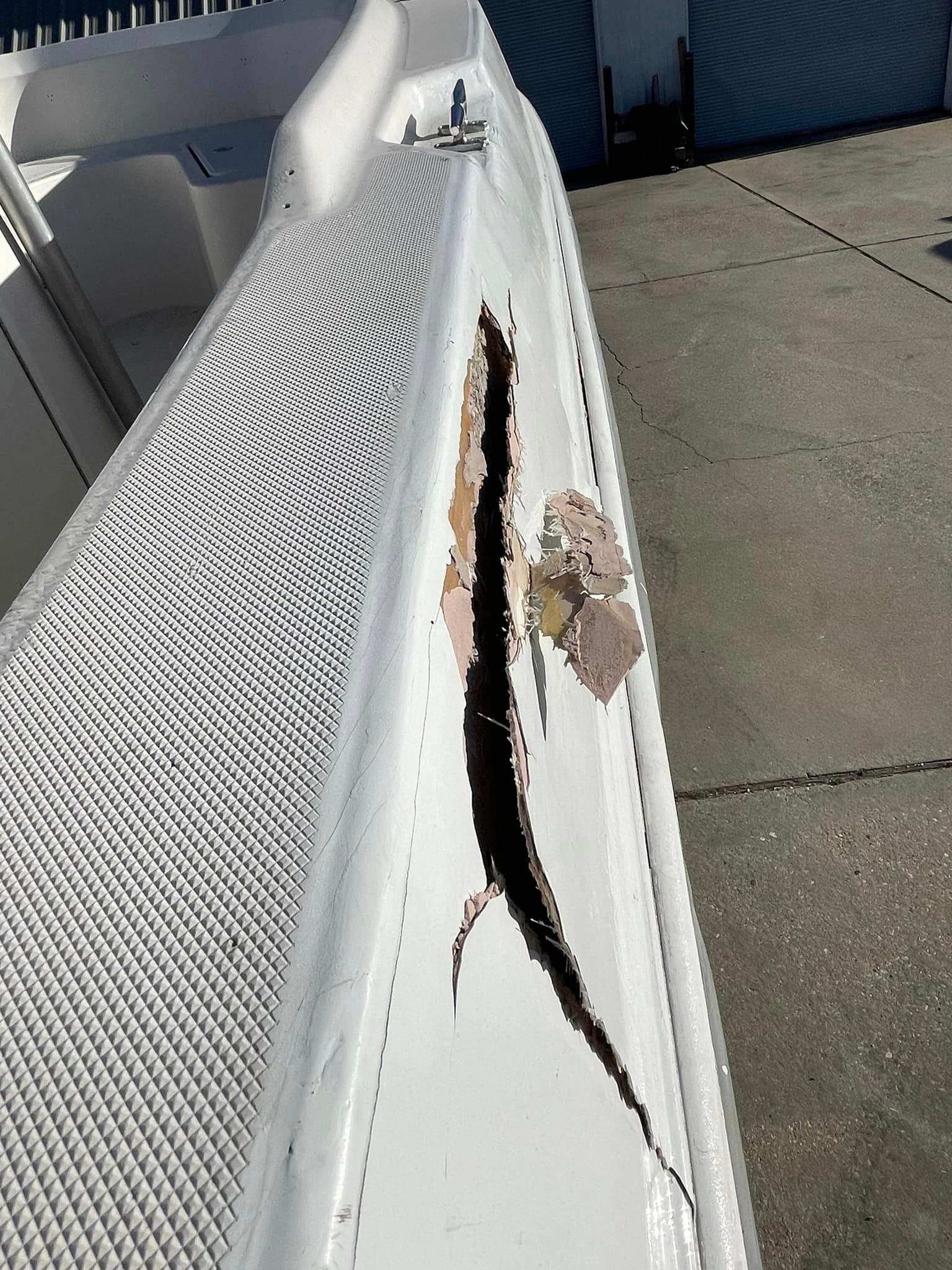 Damaged white bench with a large torn crack along the seat edge outdoors