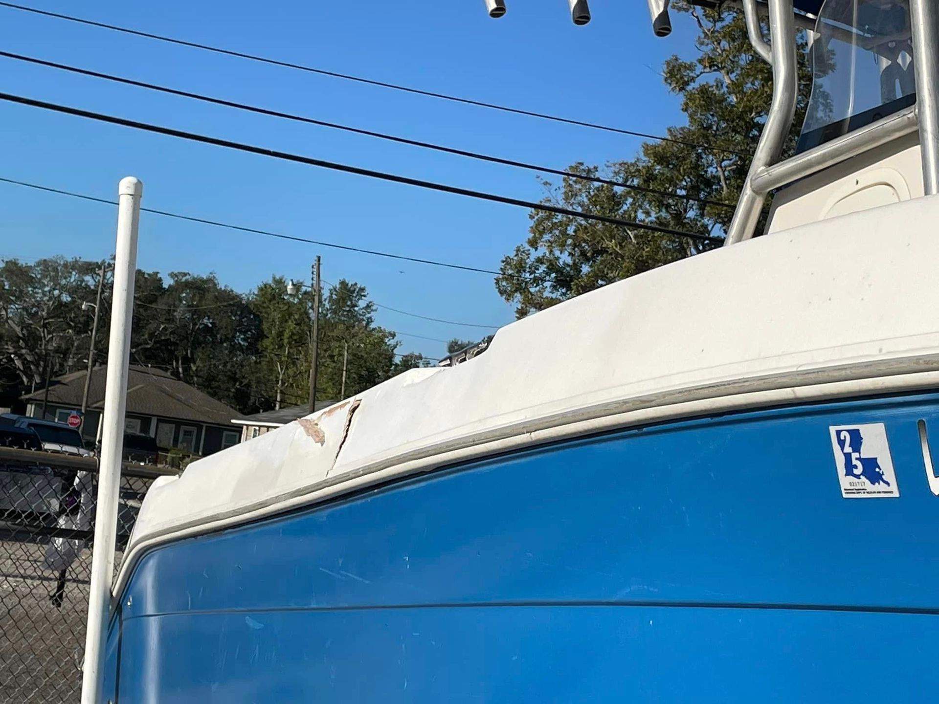 Blue boat docked beside a fence under a clear sky