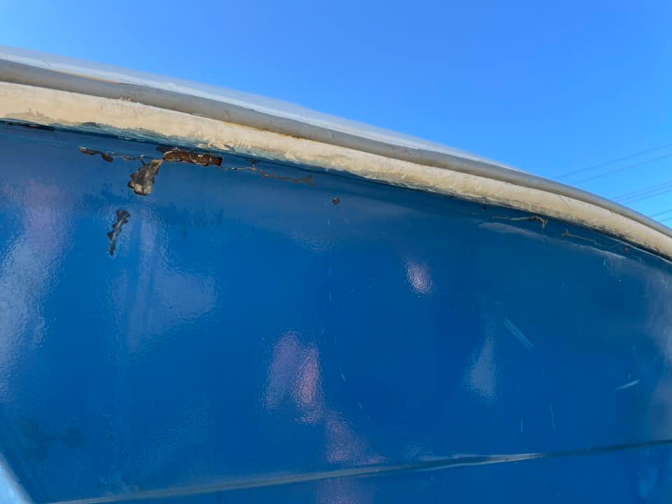 Close-up of a scratched blue vehicle panel under a clear sky