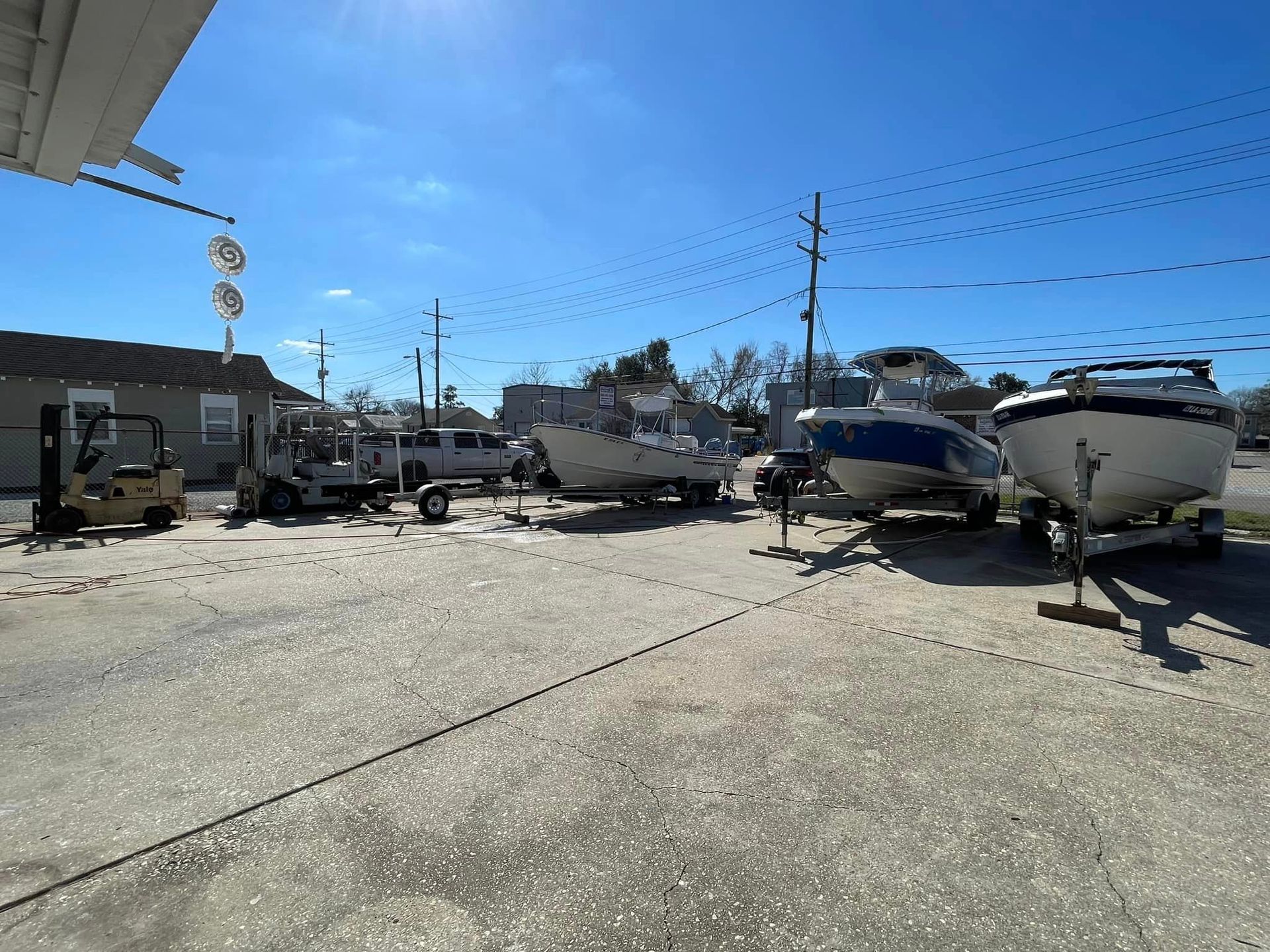 Boat yard with several boats on trailers under a bright blue sky